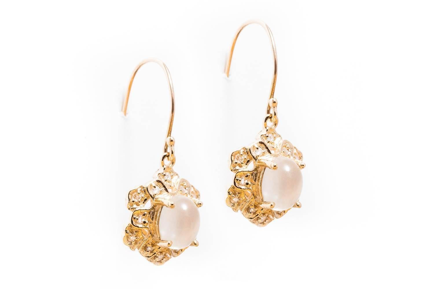 A beautiful pair of dangling diamond and moonstone earrings in 9 carat yellow gold. Centering these earrings are a pair of beautiful moonstones surrounded by sparkling antique rose cut diamonds.

Of beautiful quality, the inclusion free blue sheen