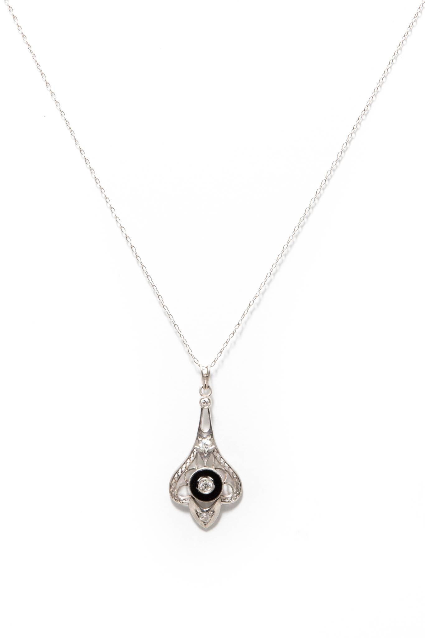 A beautiful original art deco period diamond and onyx pendant necklace in luxurious platinum.  Set with European cut diamonds amidst hand formed wire filigree work, this necklaces features a central jet black onyx disk set with a sparkling