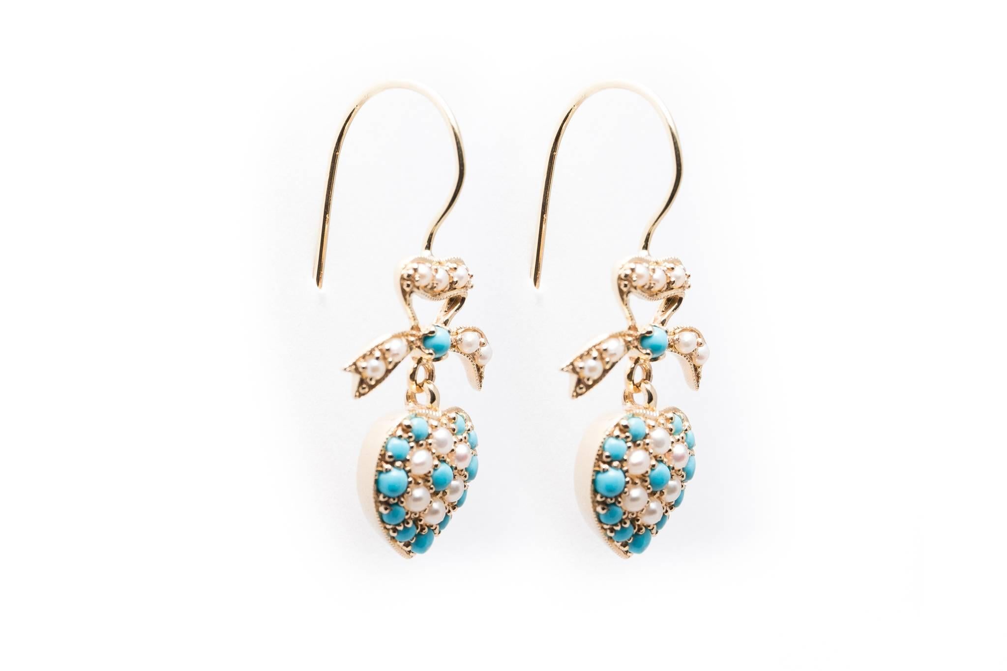 A beautiful pair of handmade dangling earrings in yellow gold.  Featuring a pearl set ribbon on the top, these earrings feature a pair of beautiful handcrafted yellow gold pearl and turquoise set hearts.

In excellent condition, these earrings