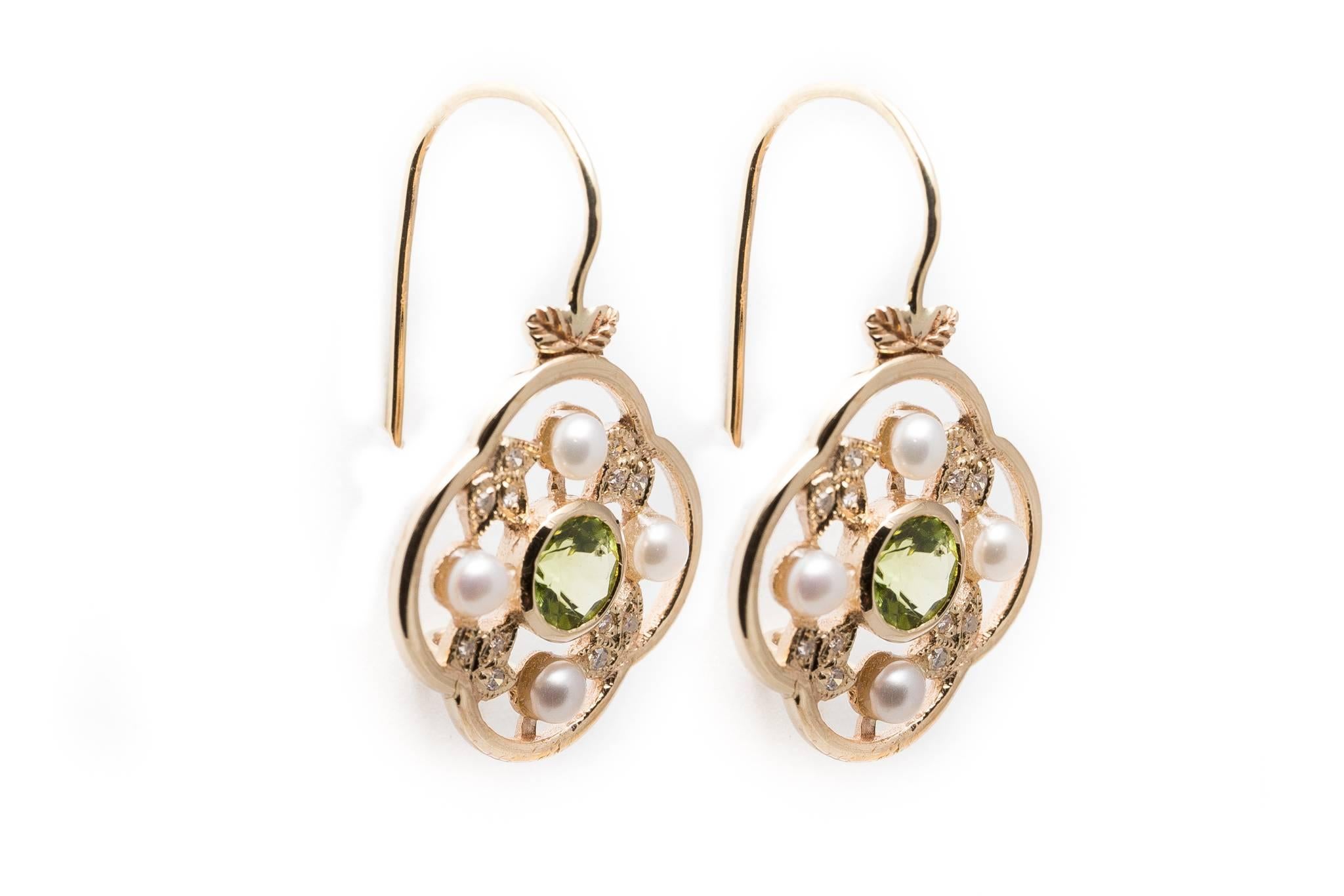 A pair of beautiful handmade floral inspired peridot, diamond, and pearl earrings in 9 carat yellow gold.  Centered by beautiful European cut peridots framed by diamond set leaves, these classic wire dangle earrings remind us of beautiful