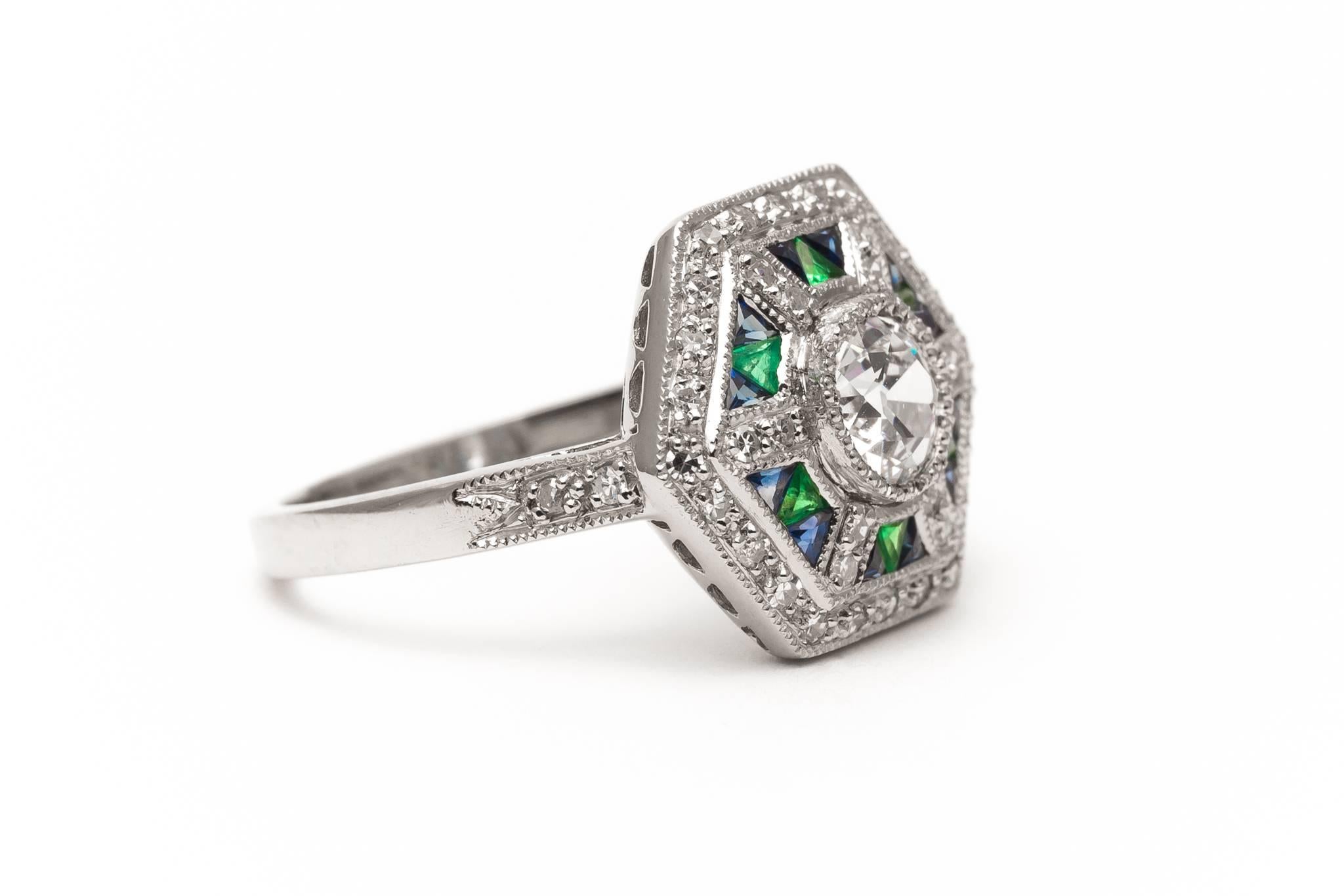 A beautiful handmade diamond, sapphire, and emerald ring in luxurious platinum.  Centered by a sparkling antique European cut diamond this ring features a halo of sparkling diamonds and bespoke French cut emerald and sapphires.

Grading as superb VS