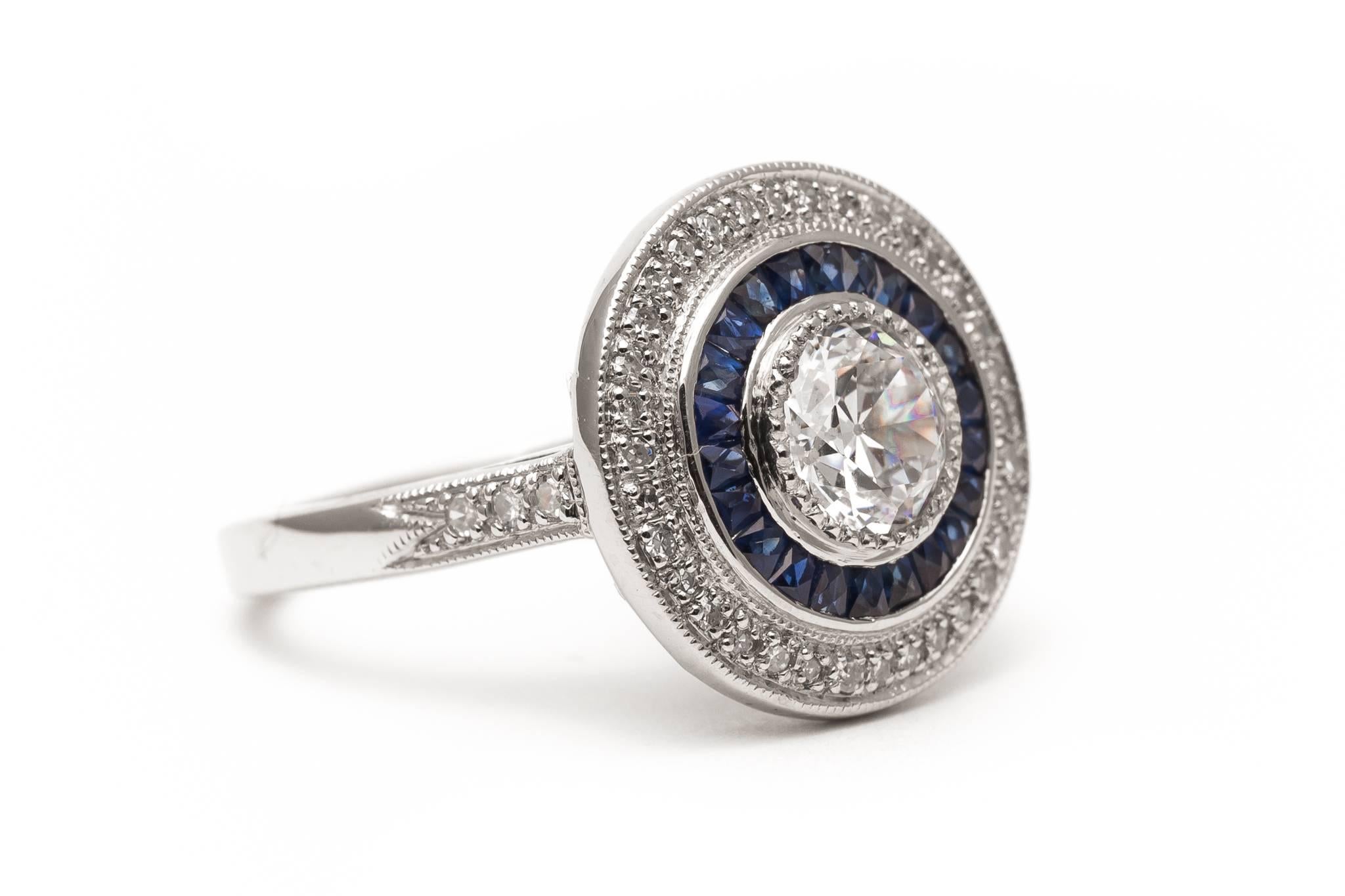 A ring with a unique twist on the traditional diamond target style engagement ring.  Featuring a center antique European cut diamond framed by rich blue French cut sapphires, this ring also features a unique outer row of pave set Swiss cut