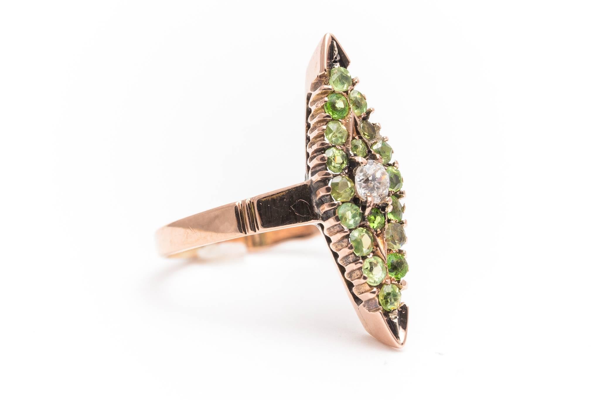 An original antique, pre Soviet era Russian made demantoid garnet and mine cut diamond ring in 14 karat (56 zolotnik) gold.  Set with a total of eighteen rare demantoid garnets found only in the Ural mountains of Russia, this ring is also centered