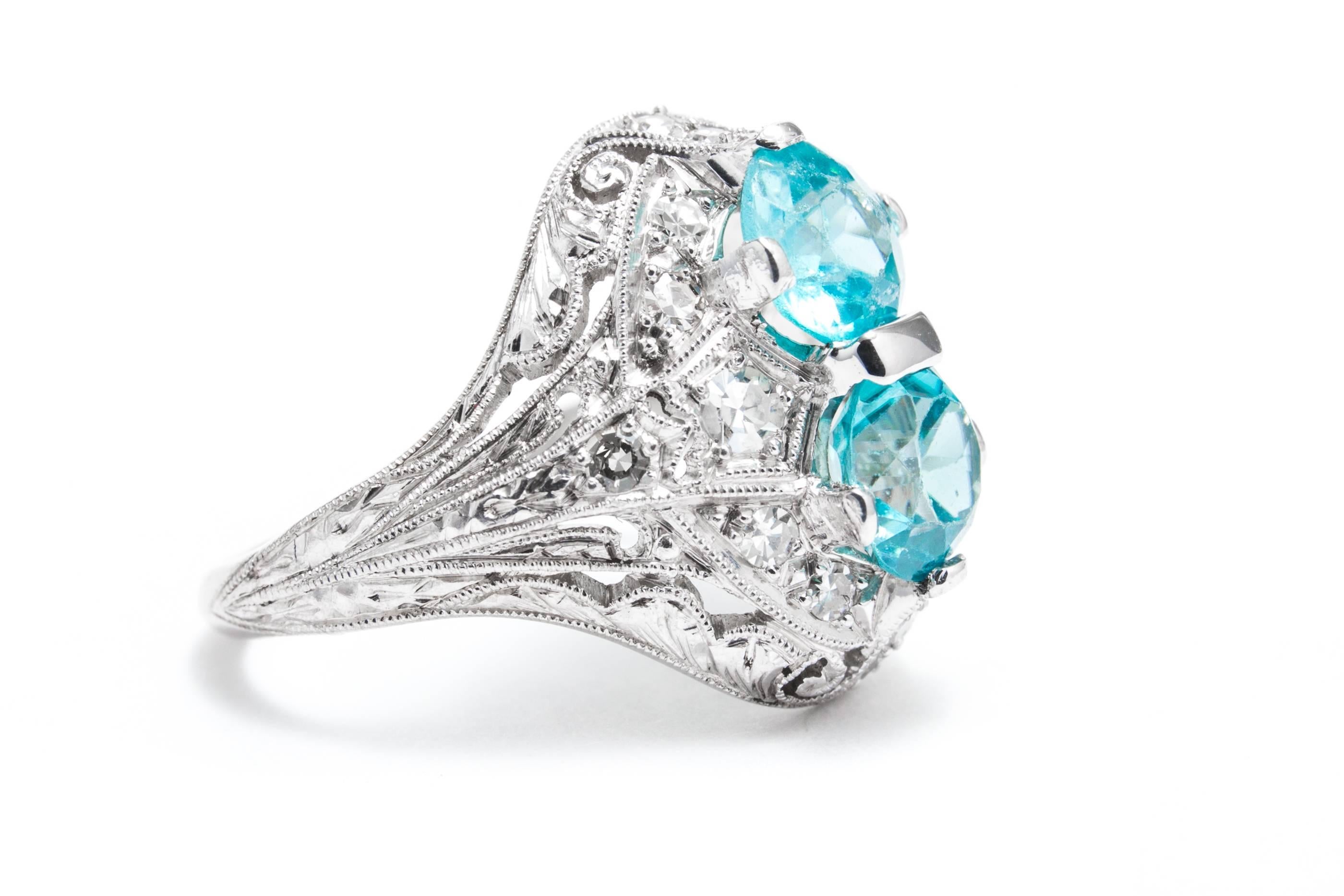A beautiful original art deco period blue zircon and diamond ring in luxurious platinum.  Centered by a pair of antique European cut blue zircons, this ring features pave set diamonds throughout along with the most beautiful hand engraving
