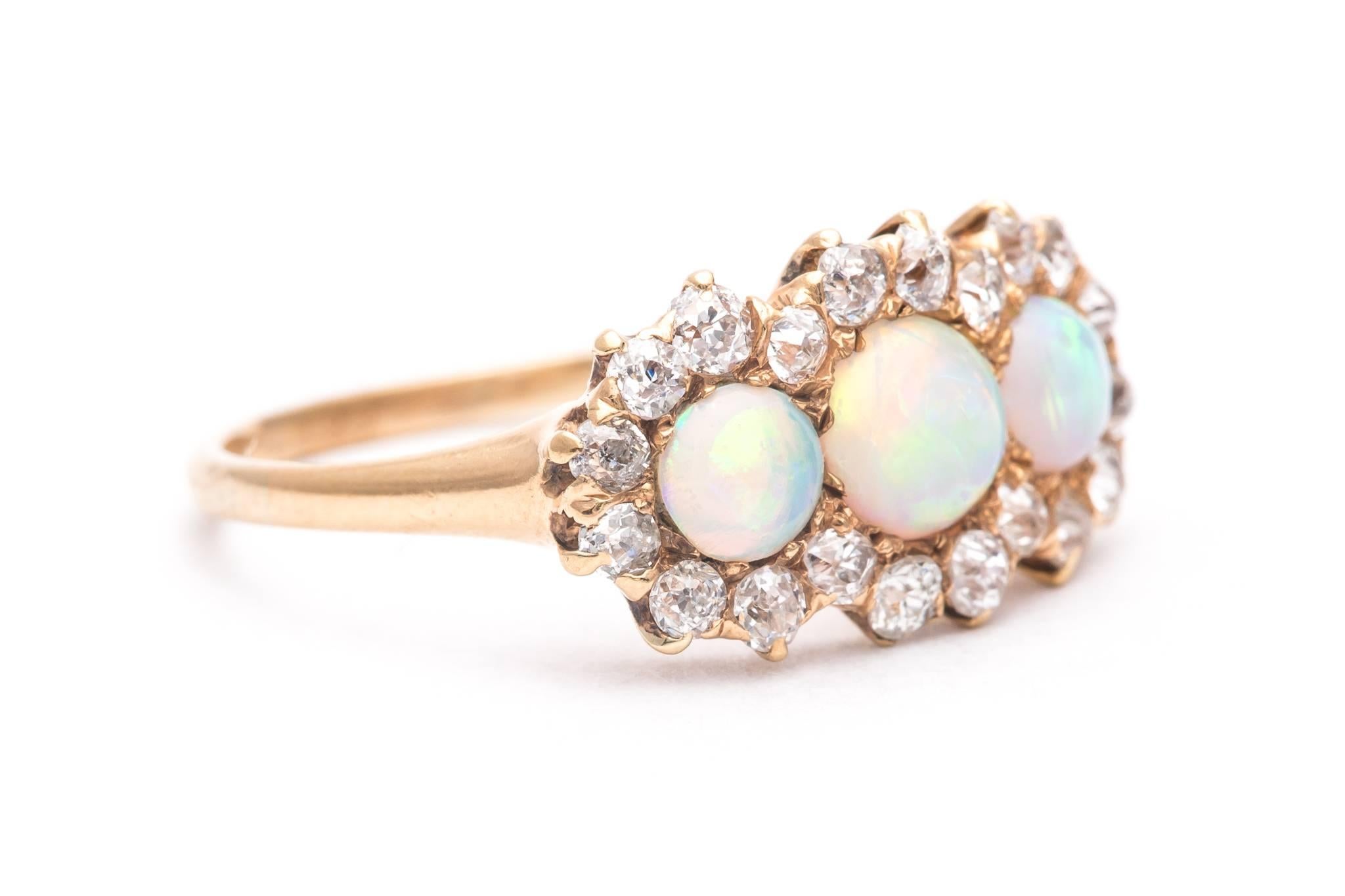 A beautiful victorian period opal, and diamond ring in 18 karat yellow gold.  Centered by a trio of rainbow like Australian opals this ring features a halo of antique mine cut diamonds surrounding the opals.

Of beautiful quality, the opals show a
