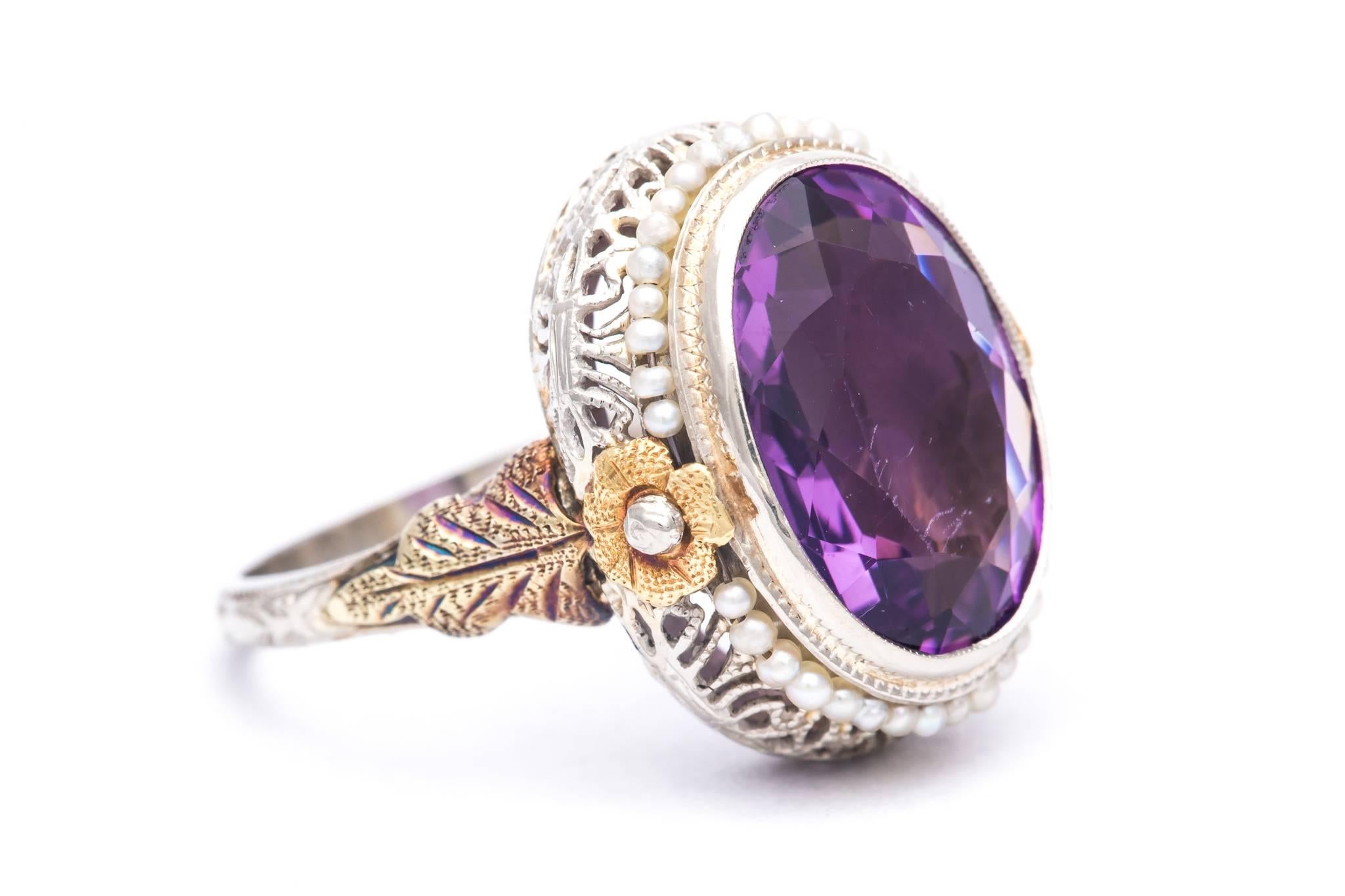 An art deco period amethyst and pearl ring in yellow and white gold.  Centered by a 13 carat oval cut amethyst surrounded by natural pearls this ring features a beautiful hand crafted and hand engraved filigree mounting in 14 karat gold.

Grading as
