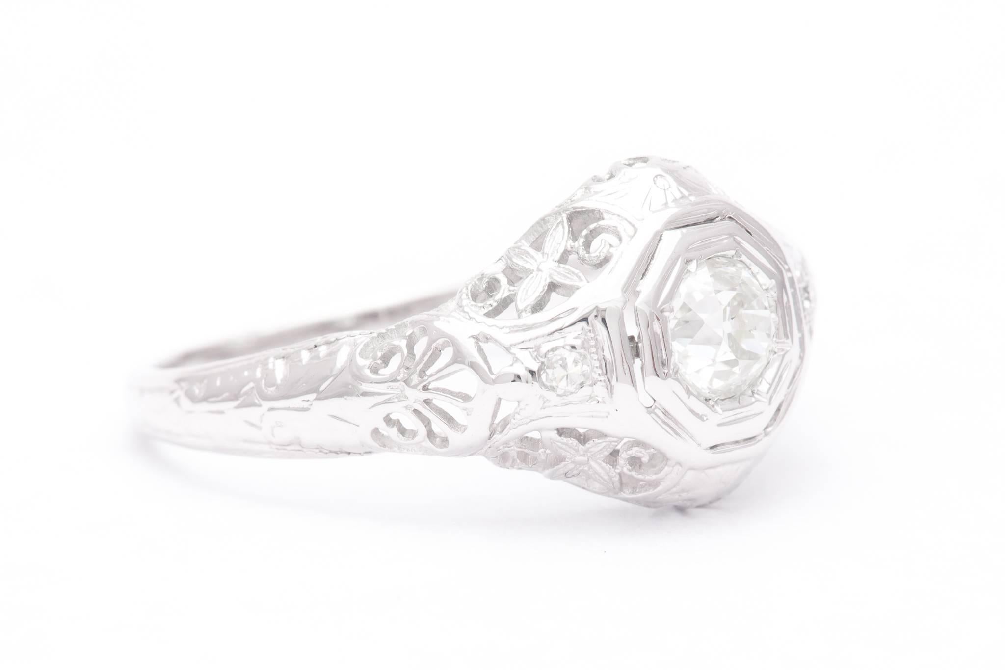 An art deco period diamond engagement ring in 18 karat white gold.  Boasting hand pierced filigree work throughout along with traditional art deco hand engraving, this ring is centered by an antique 0.50 carat European cut diamond.

Grading as H