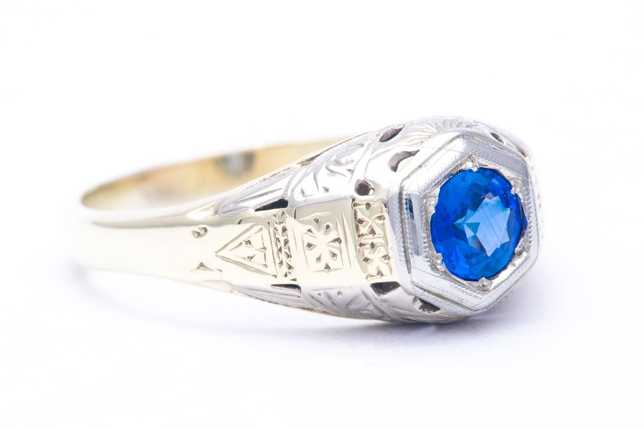 A beautiful art deco period mens sapphire ring in 14 karat white, and yellow gold.  Featuring beautiful hand engraving and a unique bi color design this ring also boasts a wonderful vivid blue center sapphire set in white gold.

Grading as VS