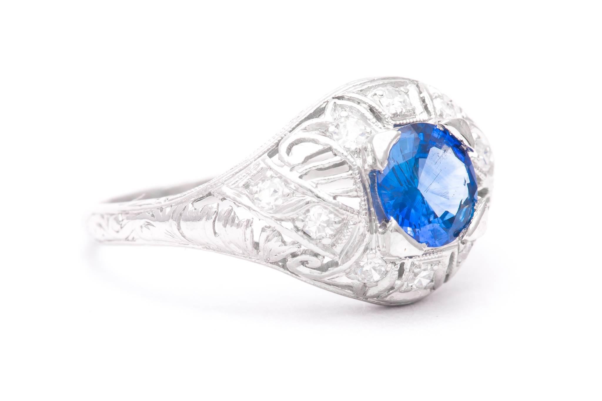 An original art deco period diamond and sapphire filigree ring in luxurious platinum.  Centered by a beautiful rich vivid blue sapphire this ring features elaborate hand pierced filigree work along with hand engraving throughout.

Grading as