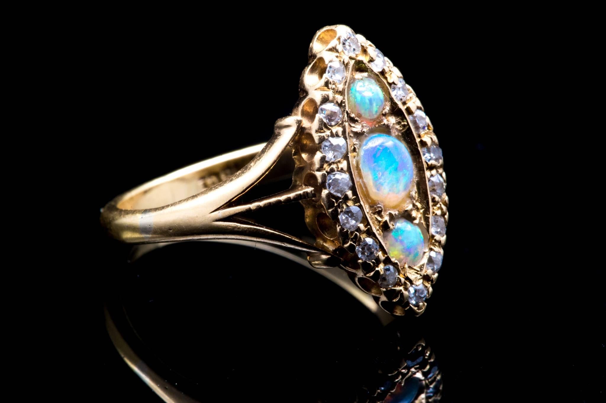 An opal and diamond trilogy ring in 18 karat yellow gold.  Centered by a trio of Australian opals this ring features a halo of pave set mine cut diamonds in rich 18 karat yellow gold.  

Grading as beautiful VS/SI clarity and G/H color, the antique