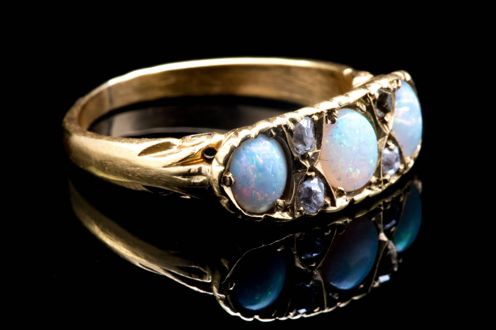 A victorian period opal, and mine cut diamond ring in 18 karat yellow gold.  Set with a trio of beautiful Australian opals, this ring features hand carved scroll work and four accenting mine cut diamonds.

Grading as VS/SI1 clarity and G/H color,