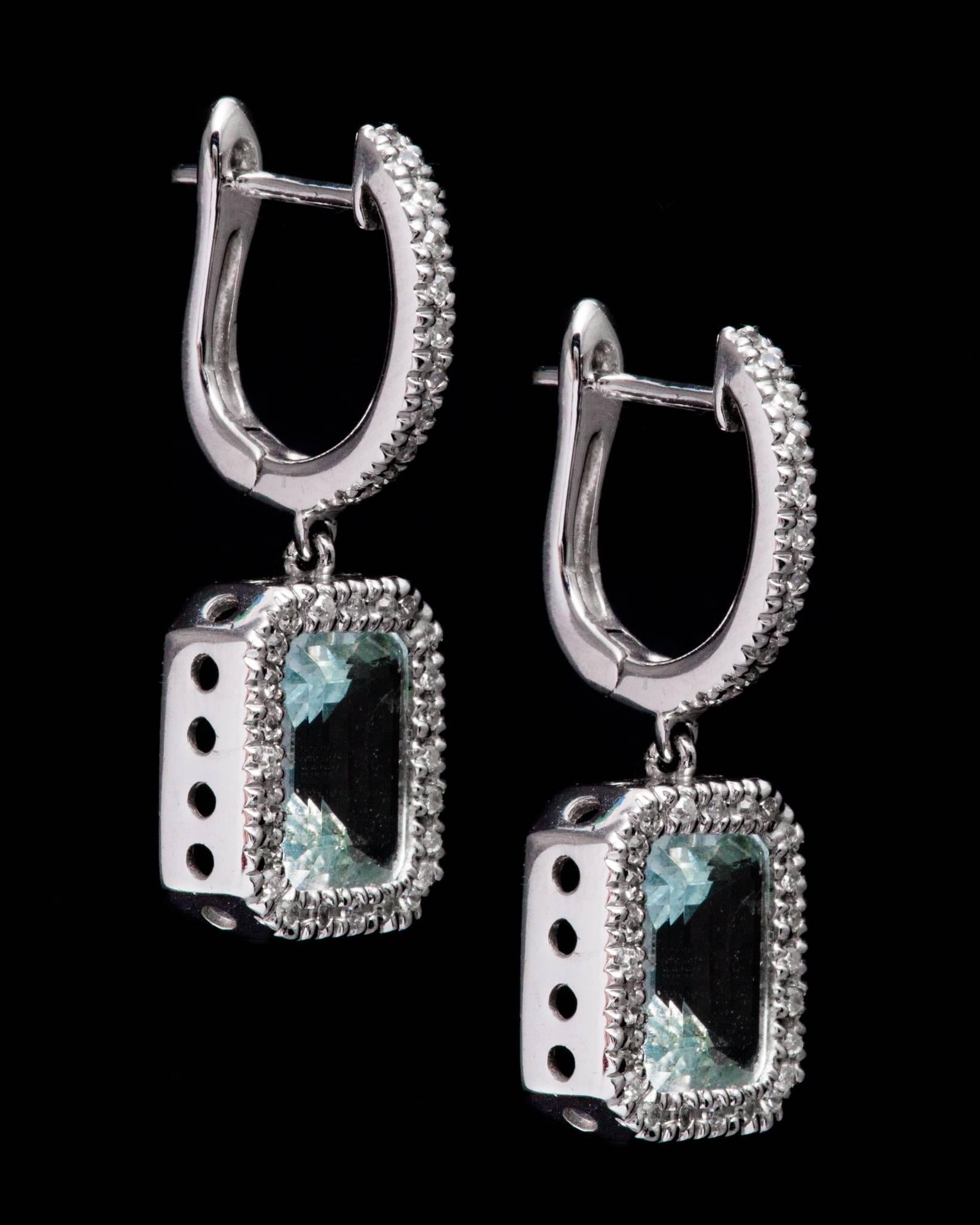 A beautiful pair of dangling aquamarine, and diamond earrings in 14 karat white gold. Each earring is centered by a 1.50 carat rich vivid sky blue aquamarine framed by sparkling pave set diamonds.  

Grading as VVS clarity the vivid sky blue
