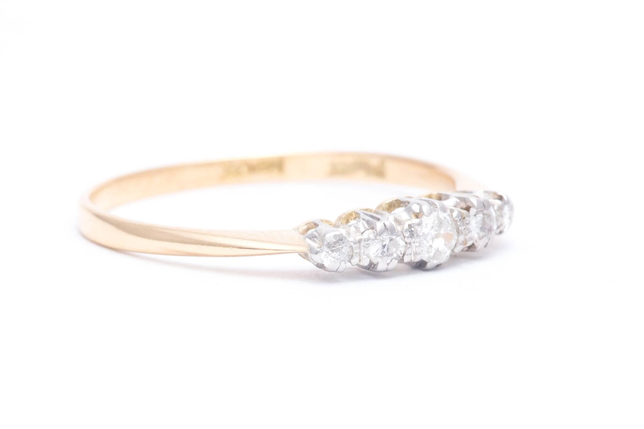 An early 20th century English made diamond wedding band in platinum and 18 karat yellow gold.  Set with five graduated antique mine cut diamonds weighing a combined 0.24 carats this ring will go perfectly with any yellow gold or platinum engagement
