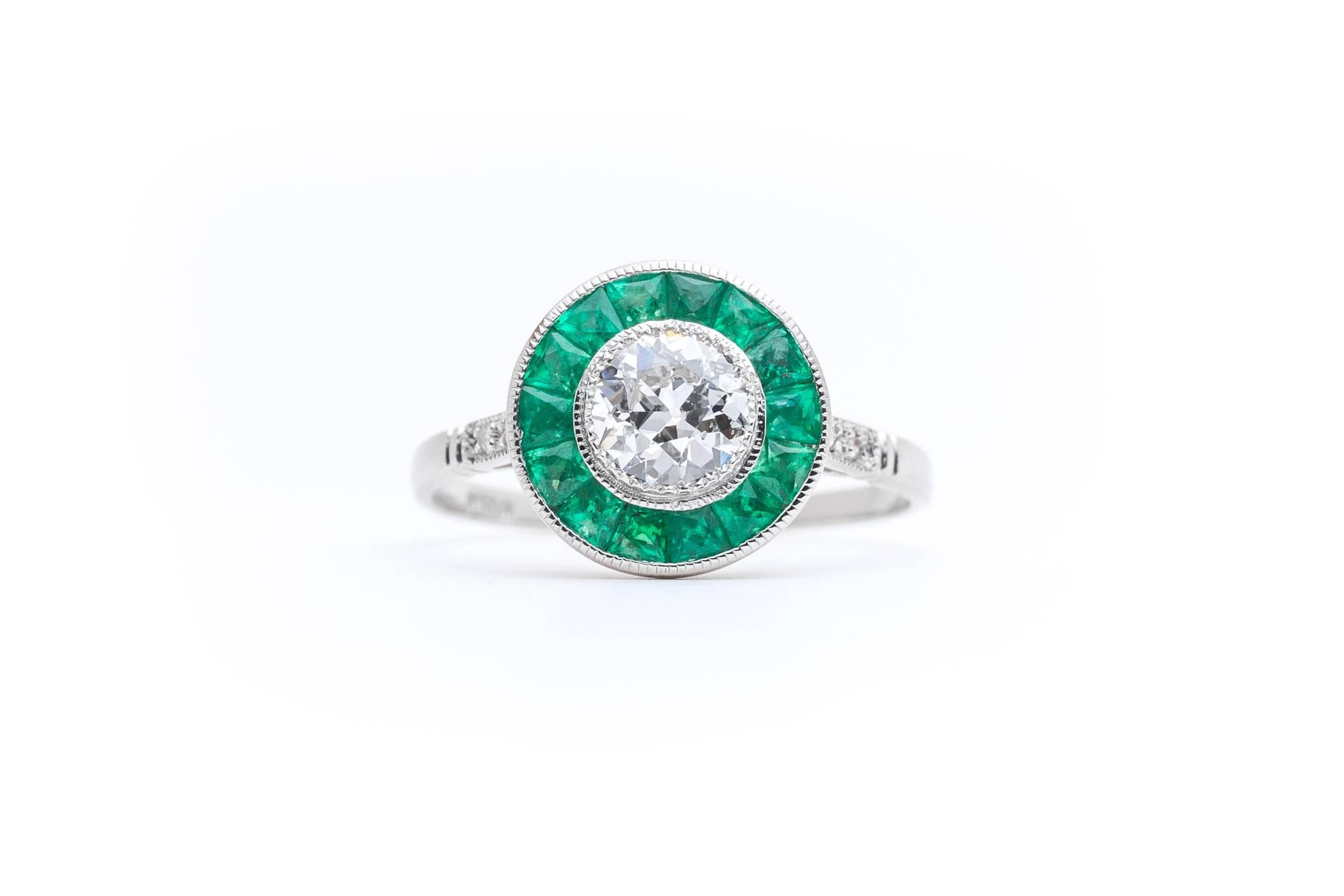 A stunning  diamond and emerald target ring in luxurious platinum. Completely hand crafted, this stunning target ring is a prime example of a French style engagement ring. Centered by a single antique European cut diamond surrounded by rich green