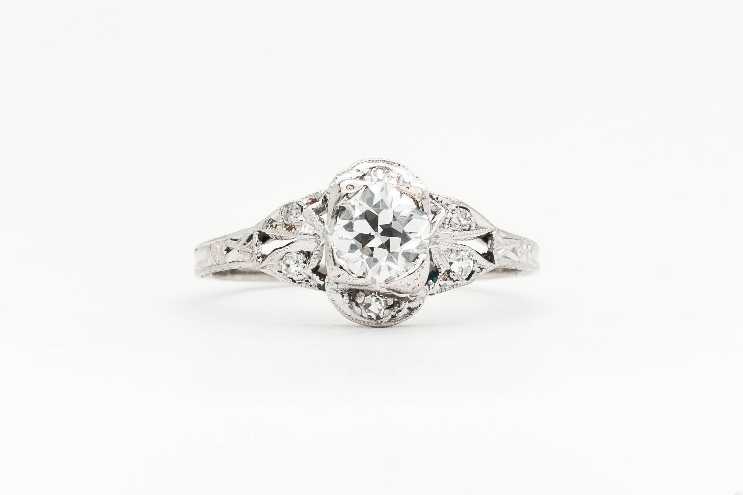 A beautiful art deco period diamond engagement ring in luxurious platinum. Centered by a sparkling old European cut diamond of very fine quality, this ring features a beautifully hand engraved platinum mounting adorned with accenting diamonds