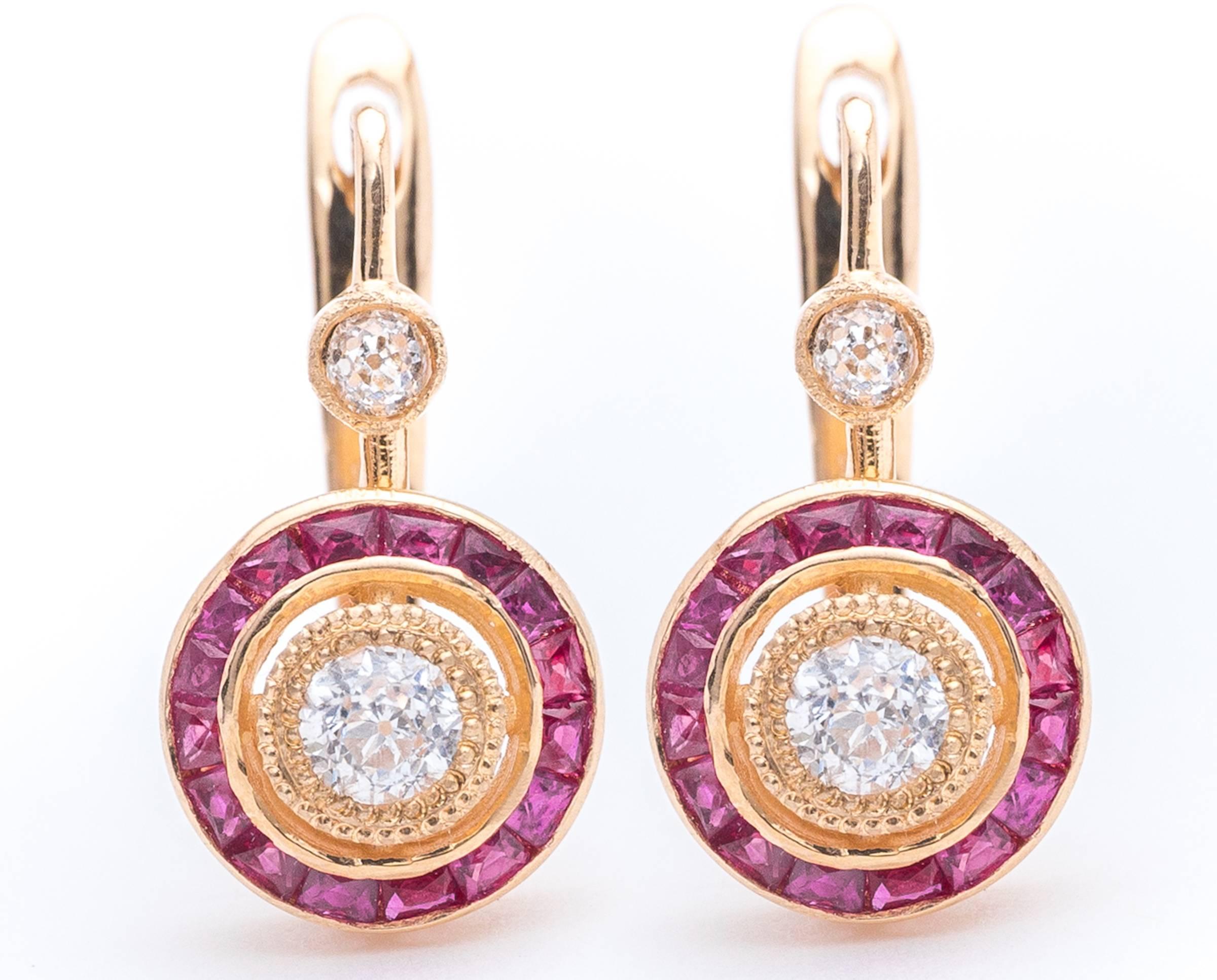 A pair of beautiful target style diamond and ruby earrings in 14 karat yellow gold. Centered by a pair of old European cut diamonds these diamonds feature halos of French cut vivid red rubies surrounding the sparkling diamonds.

Grading as beautiful