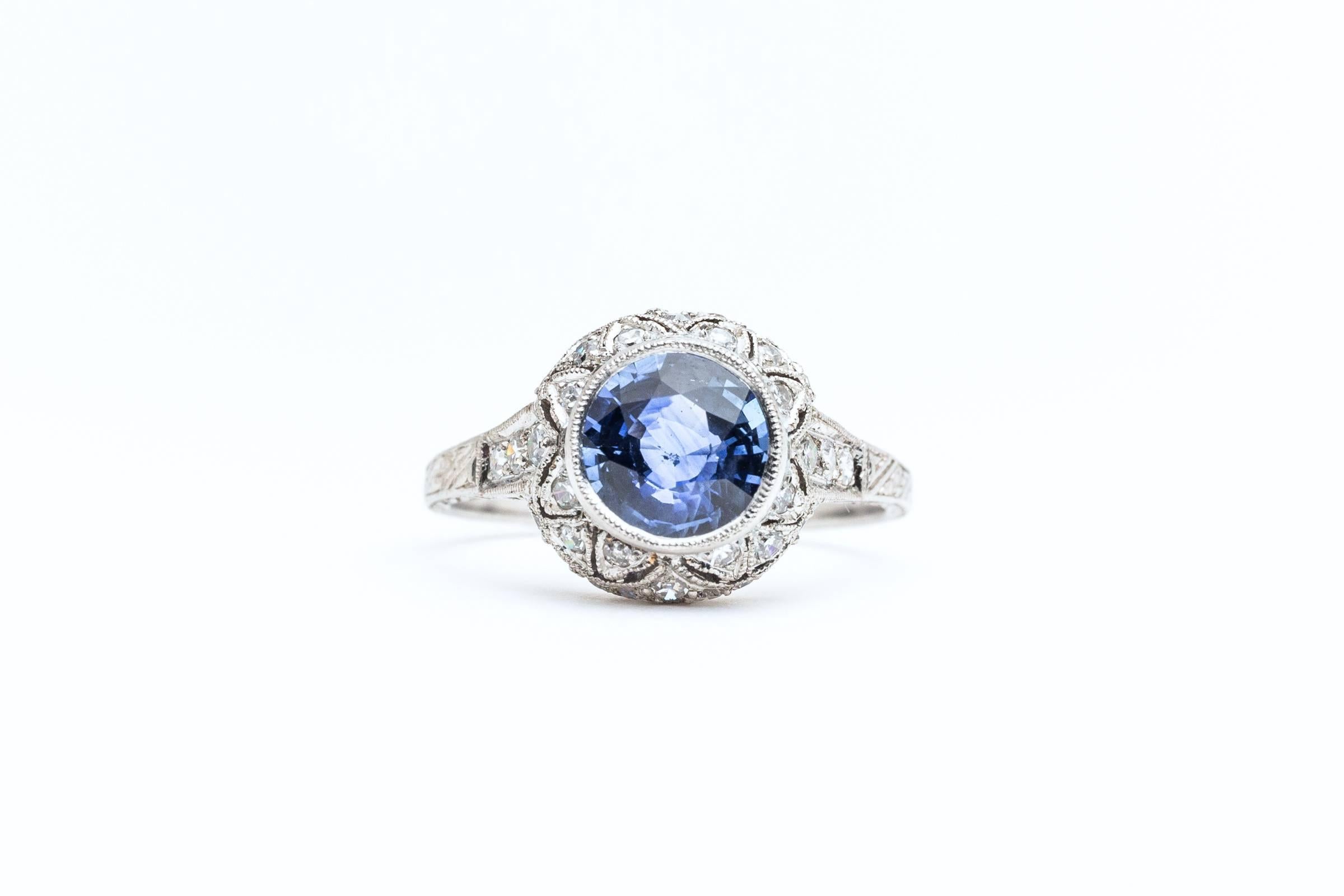 A beautiful original art deco period sapphire and diamond engagement style ring in luxurious platinum. Centered by a bezel set old European cut sapphire of exceptional quality, this ring features a total of thirty six accenting European cut diamonds