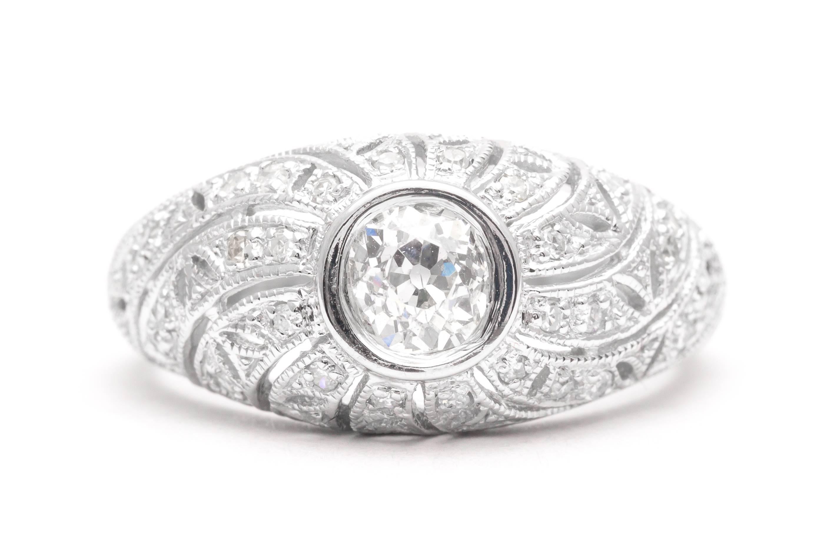 A beautiful swirl design diamond filigree ring in 14 karat white gold. Centered by a bezel set European cut diamond and set throughout with petite single cut diamonds, this ring features hand pierced filigree work along with hand engraving and mille
