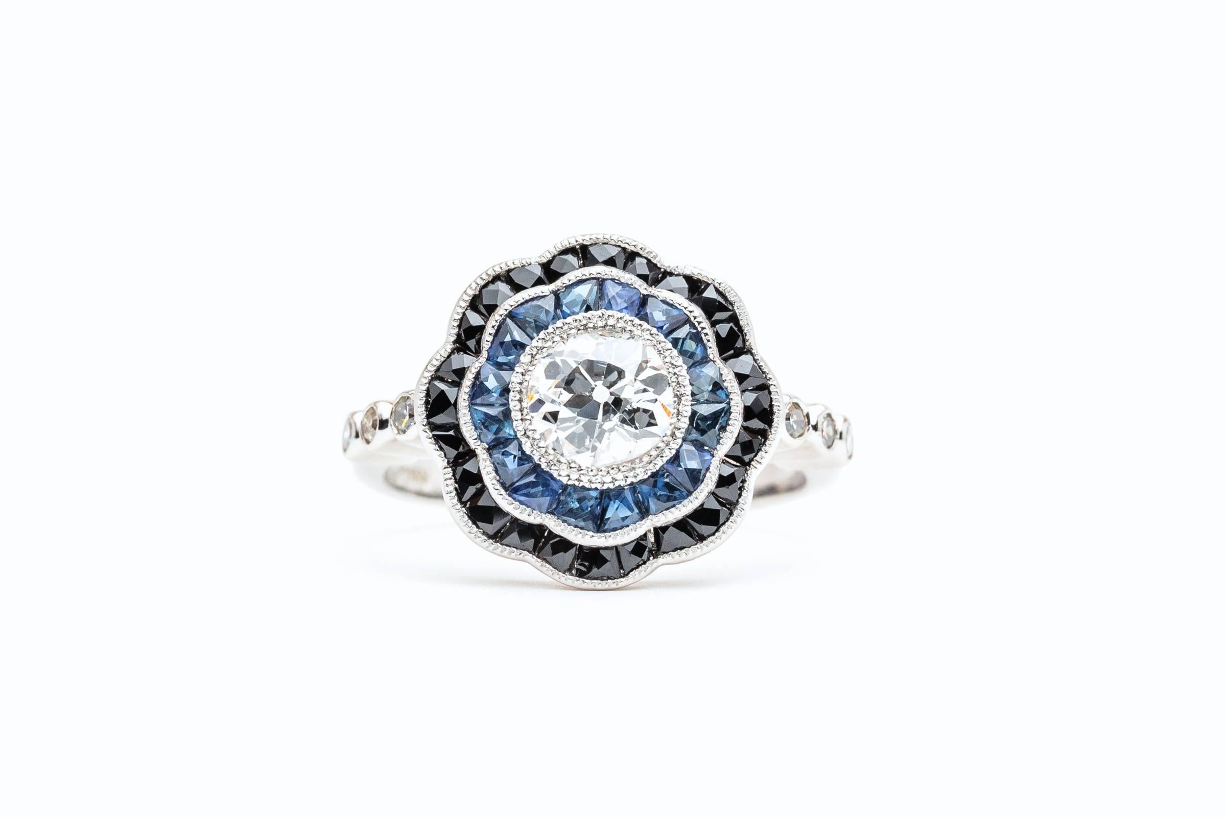 A fantastic diamond, sapphire, and onyx engagement ring in luxurious platinum. Centered by a 0.75 carat European cut diamond this ring features a double halo of Sapphires and Onyx all set in luxurious platinum.

Of gorgeous E/F colorless color, and