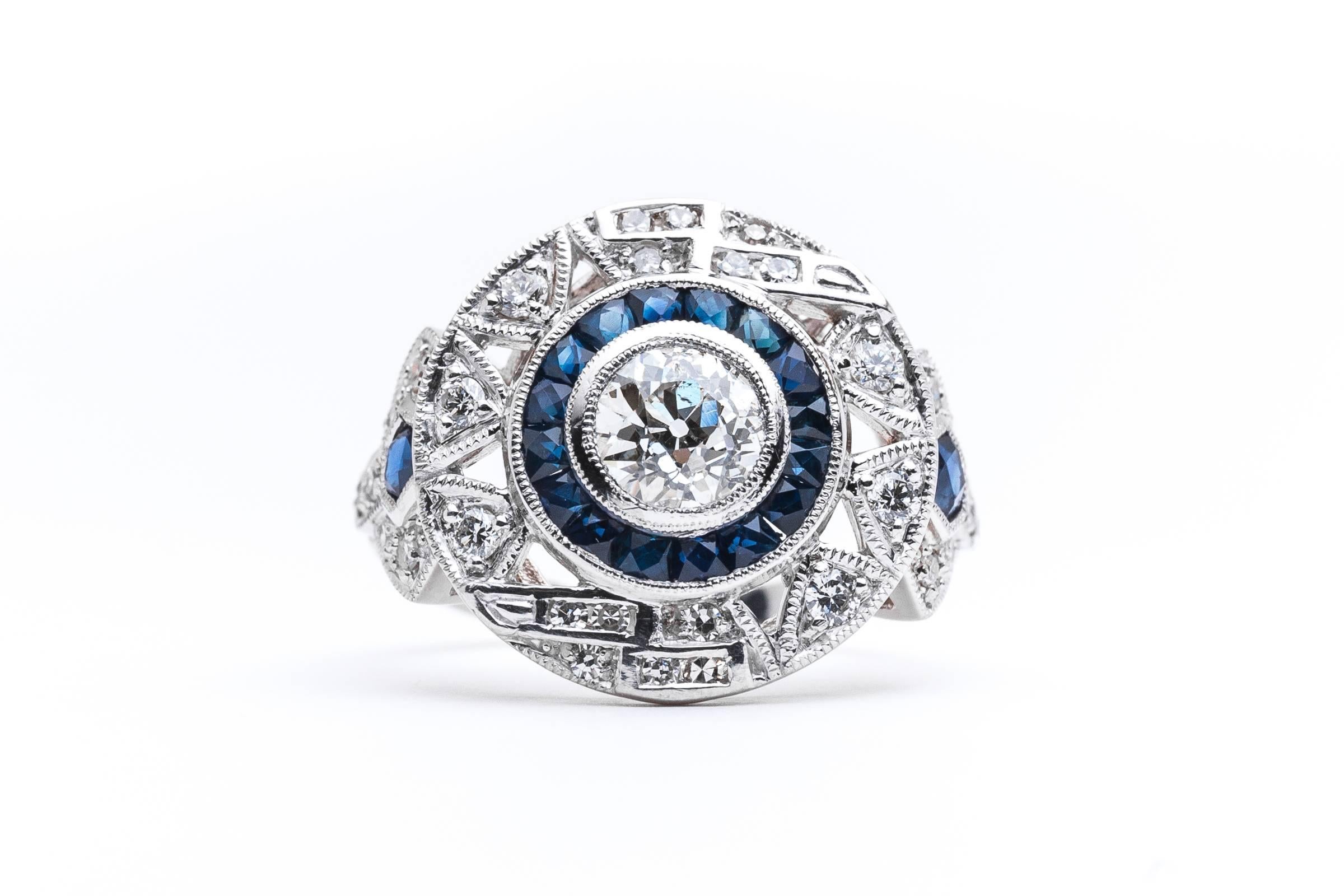 A dramatic handmade diamond and sapphire target style ring in luxurious platinum. Centered by a sparkling old European cut diamond encircled by sapphires, this ring features a variety of geometric shapes in a classic art deco style.

Grading as