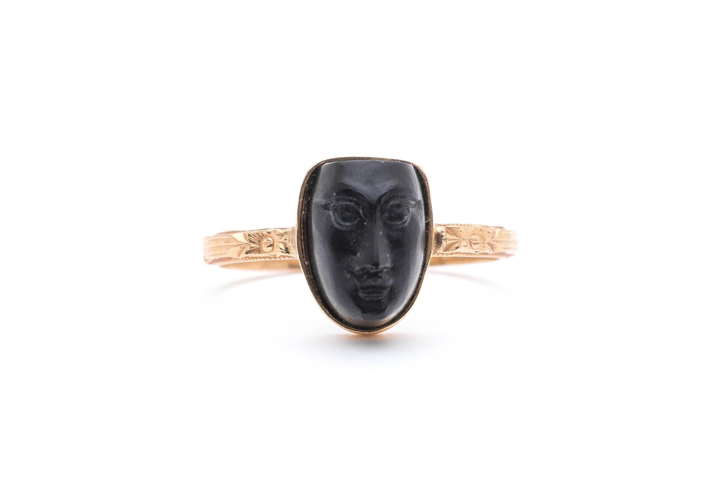 A beautiful carved Jet ring in 14 karat yellow gold dating to the art nouveau period. Featuring a striking and beautiful Egyptian style woman's face this ring sits on a beautiful hand engraved Orange Blossom pattern band in luxurious yellow