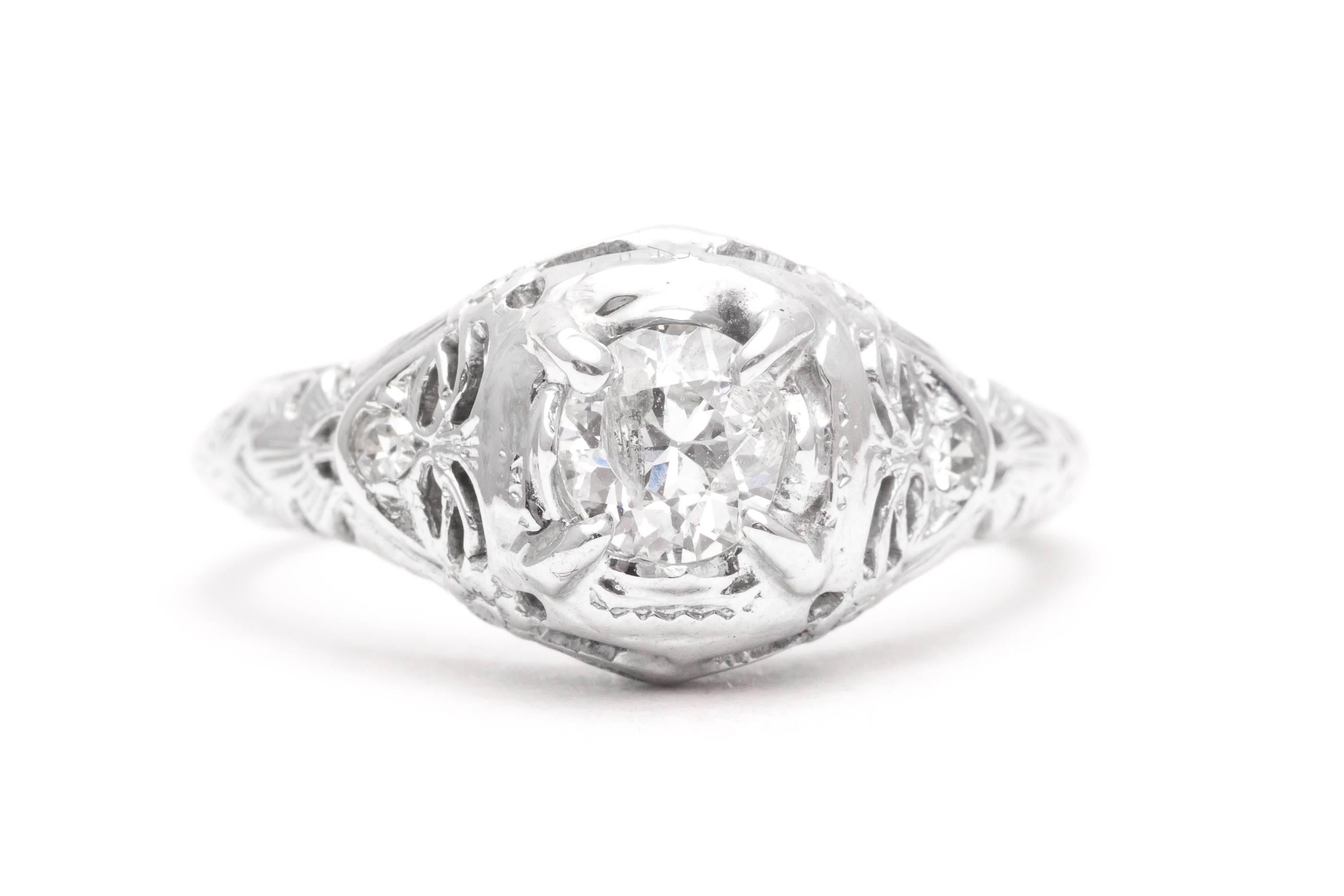 A sparkling original art deco period diamond engagement ring in 18 karat white gold. Centered by an antique European cut diamond and accented by two antique Swiss cut diamonds this ring features hand pierced filigree work complemented by hand