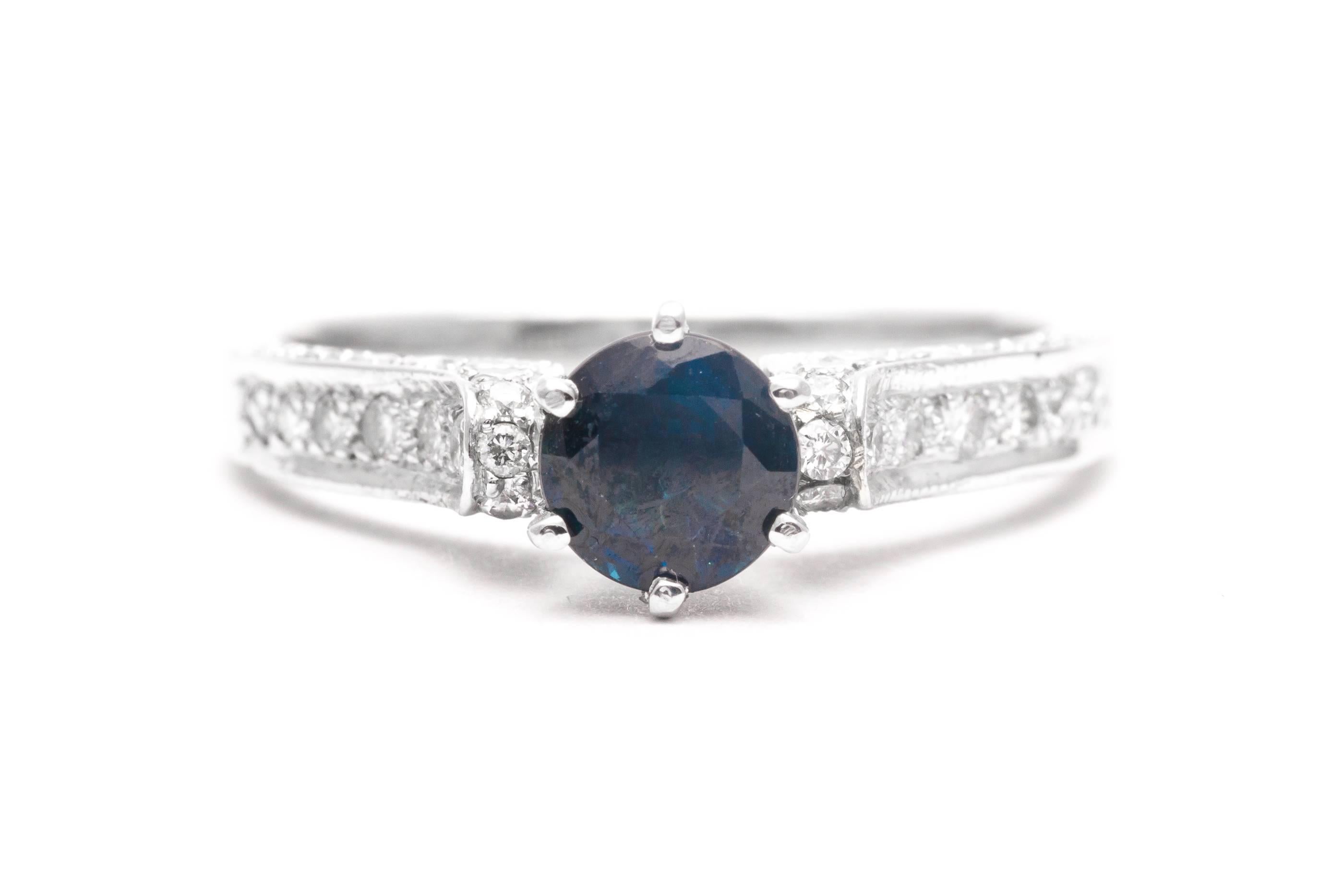 A beautiful sapphire and diamond engagement ring in 18 karat white gold.  Centered by a rich vivid blue sapphire this ring features pave set accenting diamonds throughout the luxurious 18 karat white gold mounting.

Of beautiful VS clarity and rich