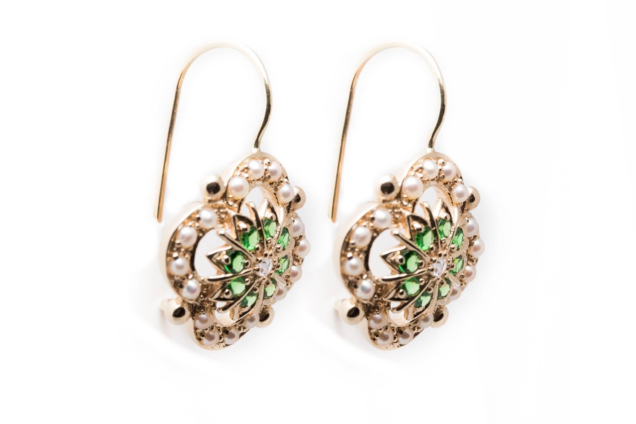 A beautiful pair of diamond, demantoid garnet, and pearl earrings in yellow gold.  Centered by a sparkling antique rose cut diamond encircled by demantoid garnets these earrings feature an outer halo of pearls.

Of beautiful quality, the center