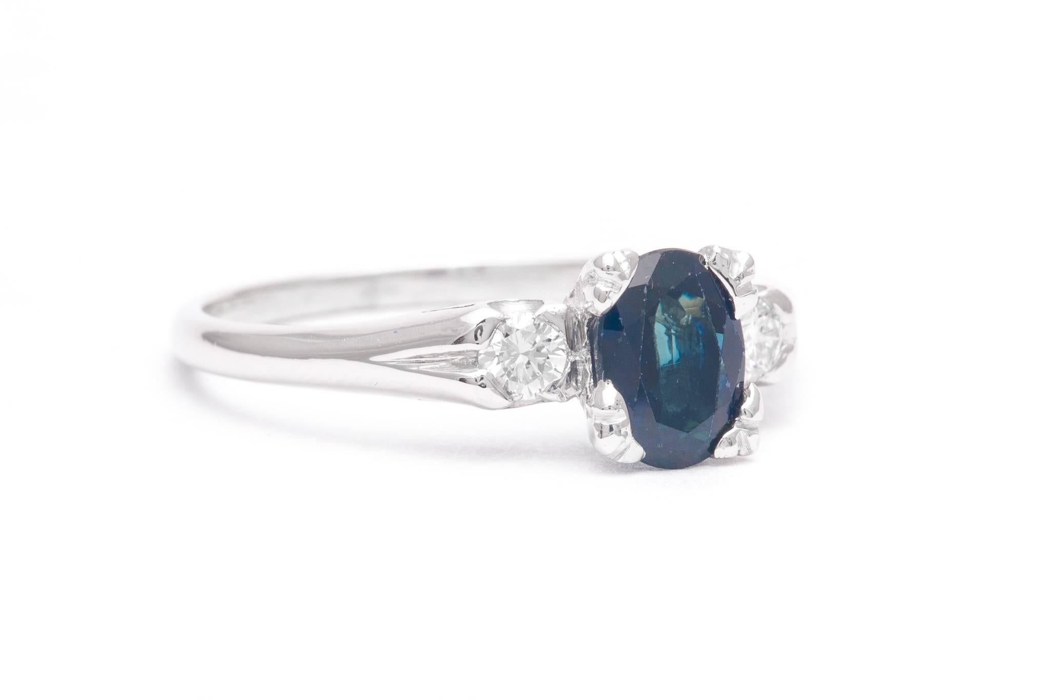 A vintage mid century American sapphire and diamond three stone ring in luxurious platinum.  Centered by a 1.15 carat cushion shaped sapphire this ring features a pair of brilliant cut diamonds framing the center sapphire.

Grading as beautiful rich