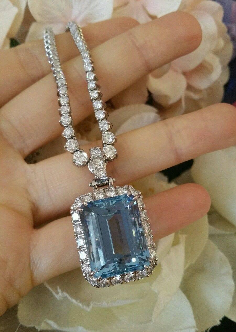 28.61 ct Aquamarine set in a custom designed diamond halo setting with diamond bail in 18k white gold.  The pendant has an ornate back gallery with floral motif.  There are 26 round brilliant cut diamond, totaling 1.98 ct, quality estimated H-I