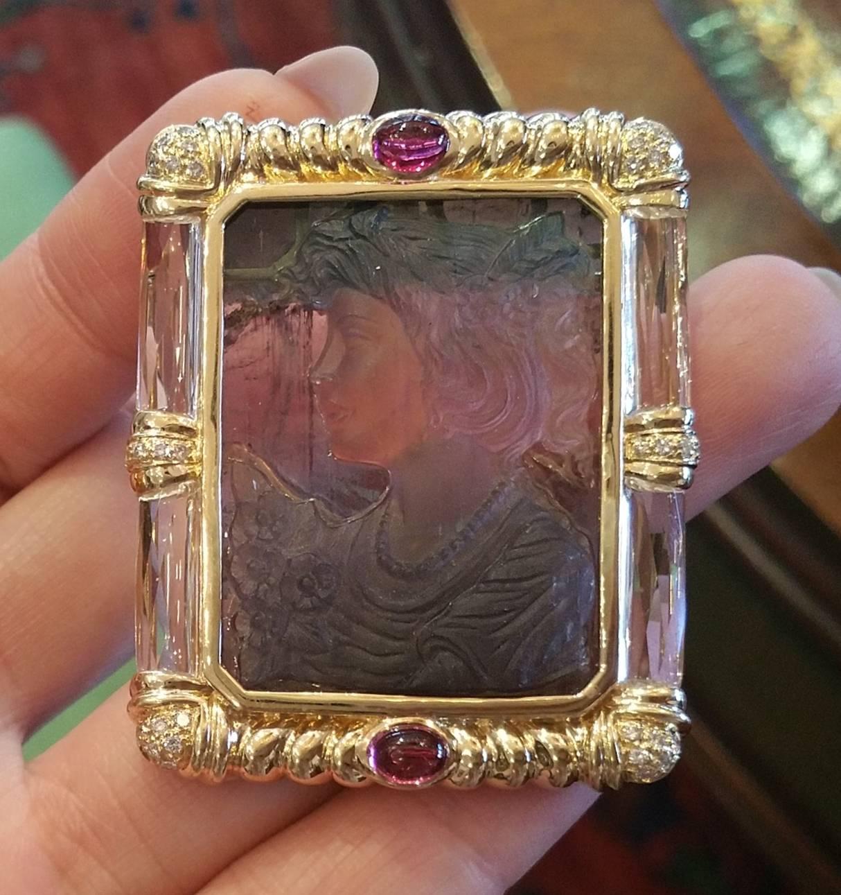 A Portrait of a Lady Brooch / pendant in 18K Yellow Gold with carved watermelon Tourmaline in the center, framed in yellow gold with 2 Tourmalines cabochons on top and bottom of the frame weighing 1.06 ct.  There are also  32 round full cut diamonds