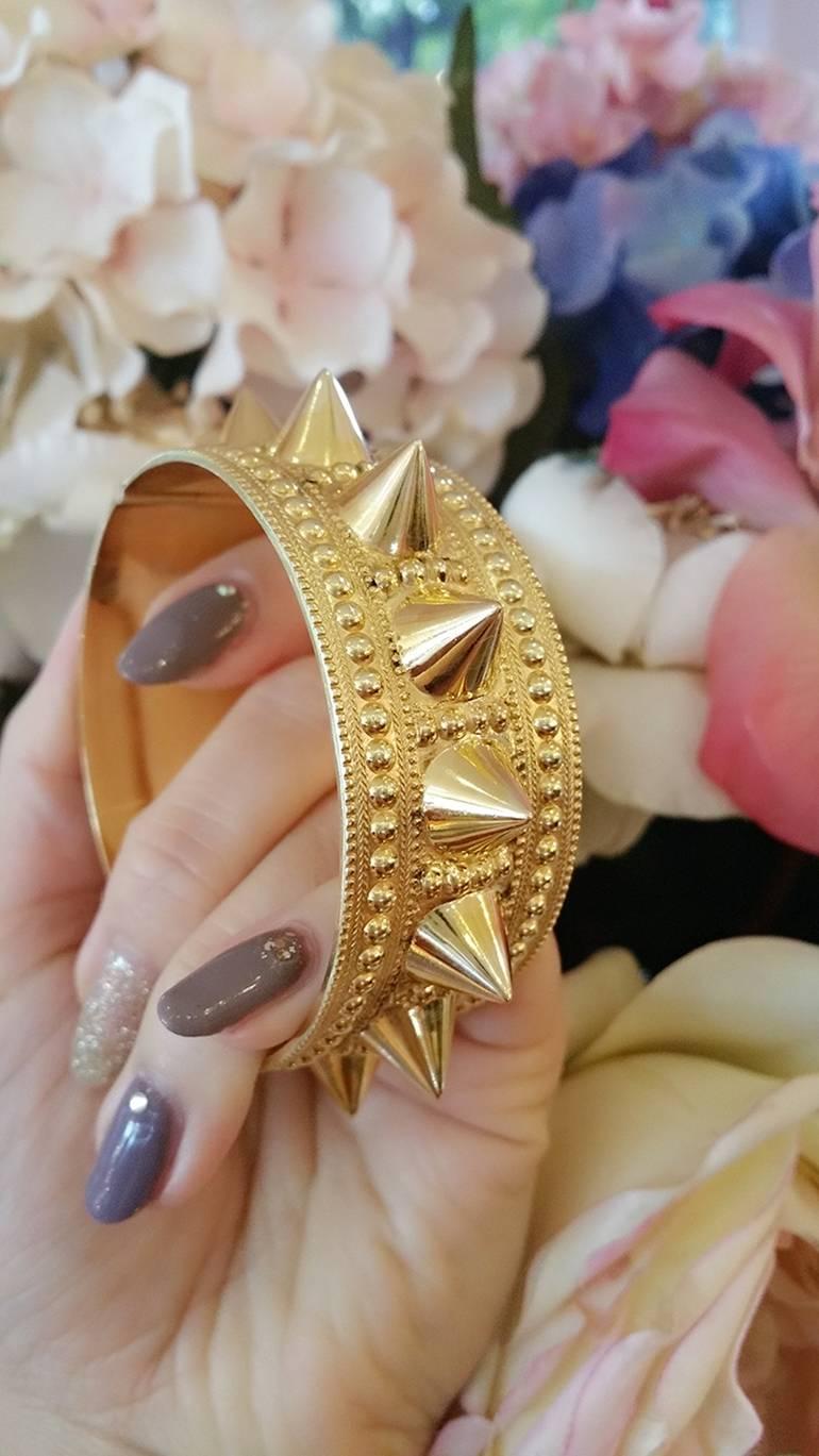 Edgy 18k Yellow Gold Spiked Bangle Bracelet is hinged with slide toggle clasp. Round shaped and wide, this beautiful bangle features fourteen high-polished spikes. Background is Etruscan-style beading and milgraining. 

Hallmarks not found--tested