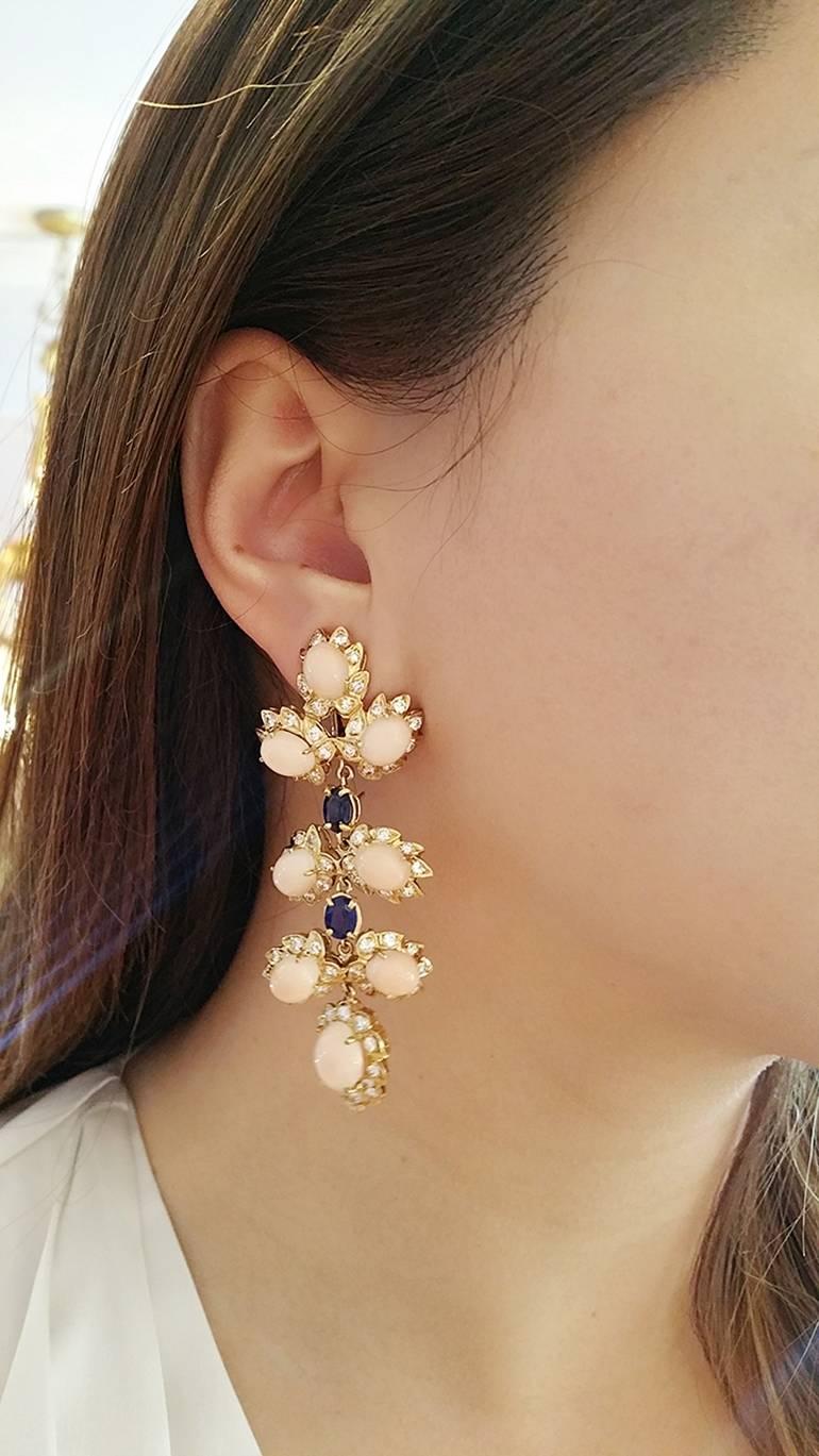 Beautiful Cluster Drop Earrings move elegantly on the ear. Comprised of Angelskin Coral surrounded by Round Diamonds in leaf design. Sections are separated by Oval Deep Blue Sapphires.
Top section of the earring can be detached for daytime use, or