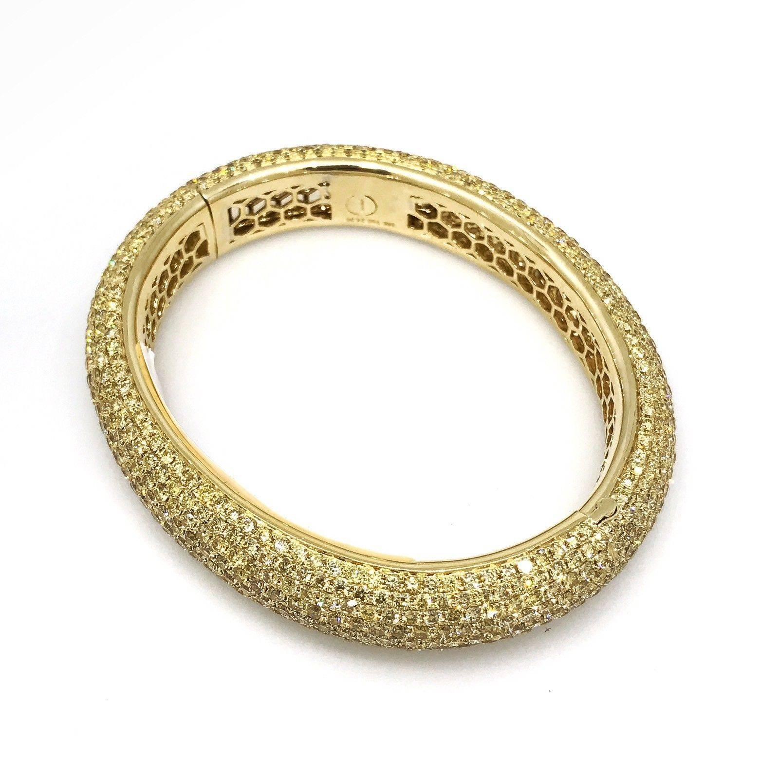 Fine quality, oval shaped wide band bangle bracelet, featuring 24.36 carats total weight of Round brilliant cut yellow diamonds, VS dlarity.  Diamonds are pave set around entire bangle in 18k high-polished yellow gold.  Bangle has an easy twisted