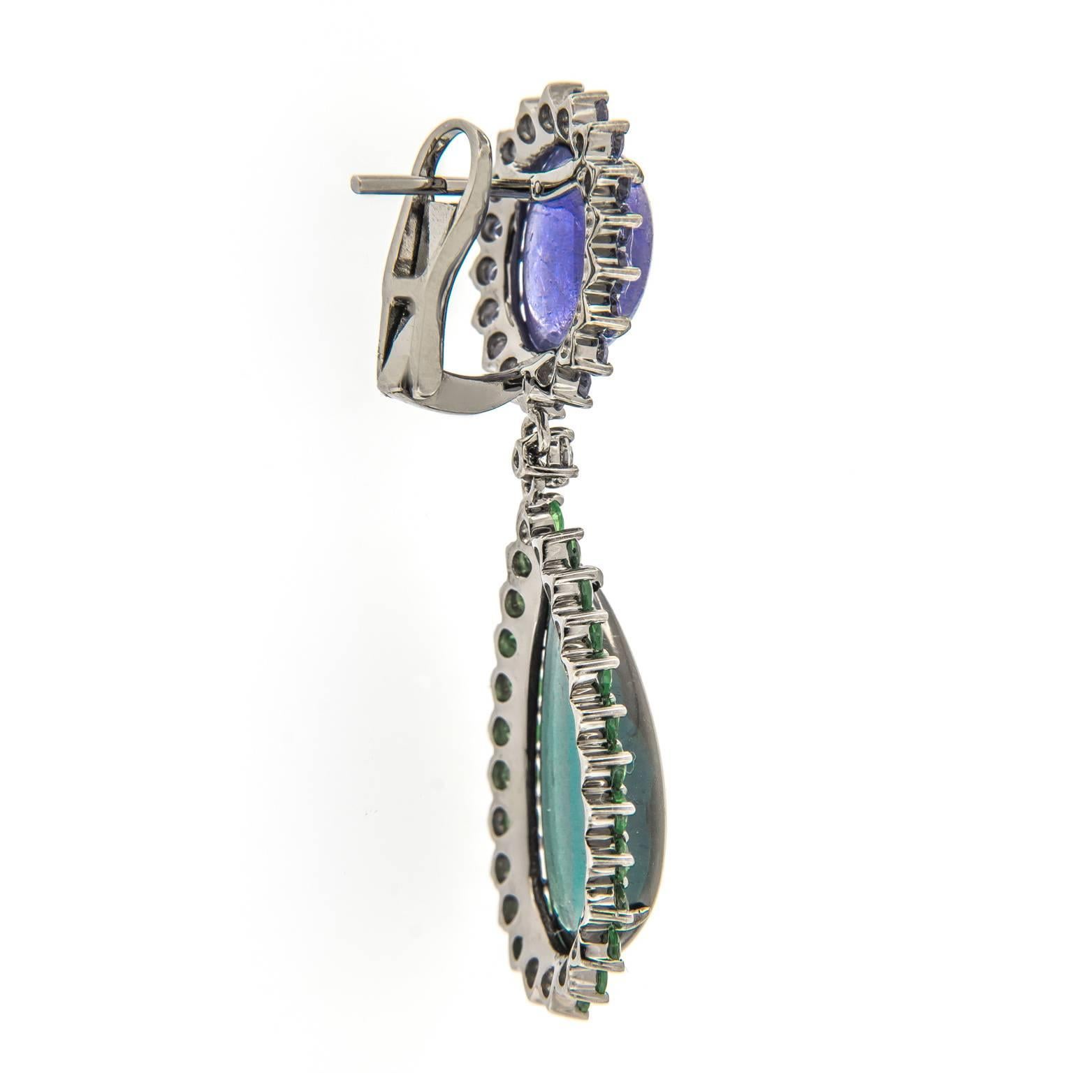 Make it an enchanted evening with these glamorous drop earrings featuring oval tanzanite framed by round tanzanites and teardrop green tourmalines framed by green garnets. Drop connected by a single round-shape diamond. Earrings crafted in 18k white