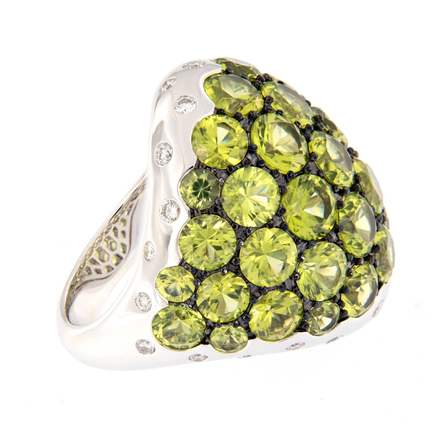 Bold and beautiful large dome cocktail ring features peridots of various sizes against a black rhodium background for striking contrast and flush set diamonds, creating a stunning look. Ring is crafted in 18k white gold. 

Ring size 6.5. (can be