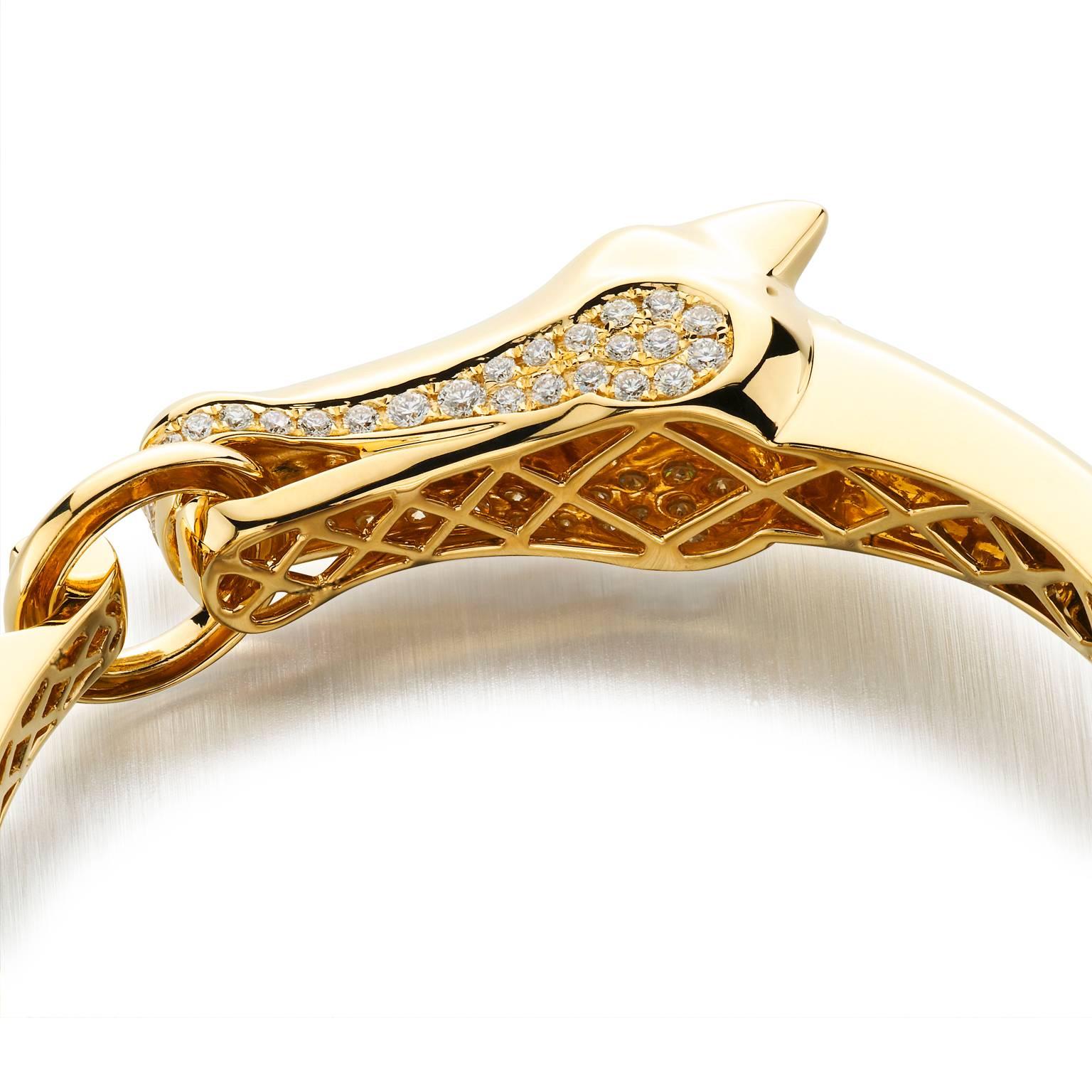 Sleek contemporary designed, heavy 18k yellow gold hinged bracelet. Features a double sided single horse head that curves around the wrist and closes with the horse head clasping a bit in it’s mouth. Accented with 2.60 cttw pave set diamonds.