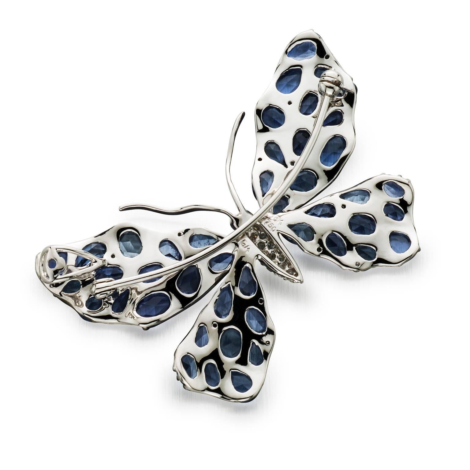 A delightful little creature to accent your lapel. Stylized 18k white gold butterfly brooch / Pendant is almost entirely set with 11.48 cttw of various sizes and shapes of blue rose cut sapphires set in black rhodium. Body is pave set with round
