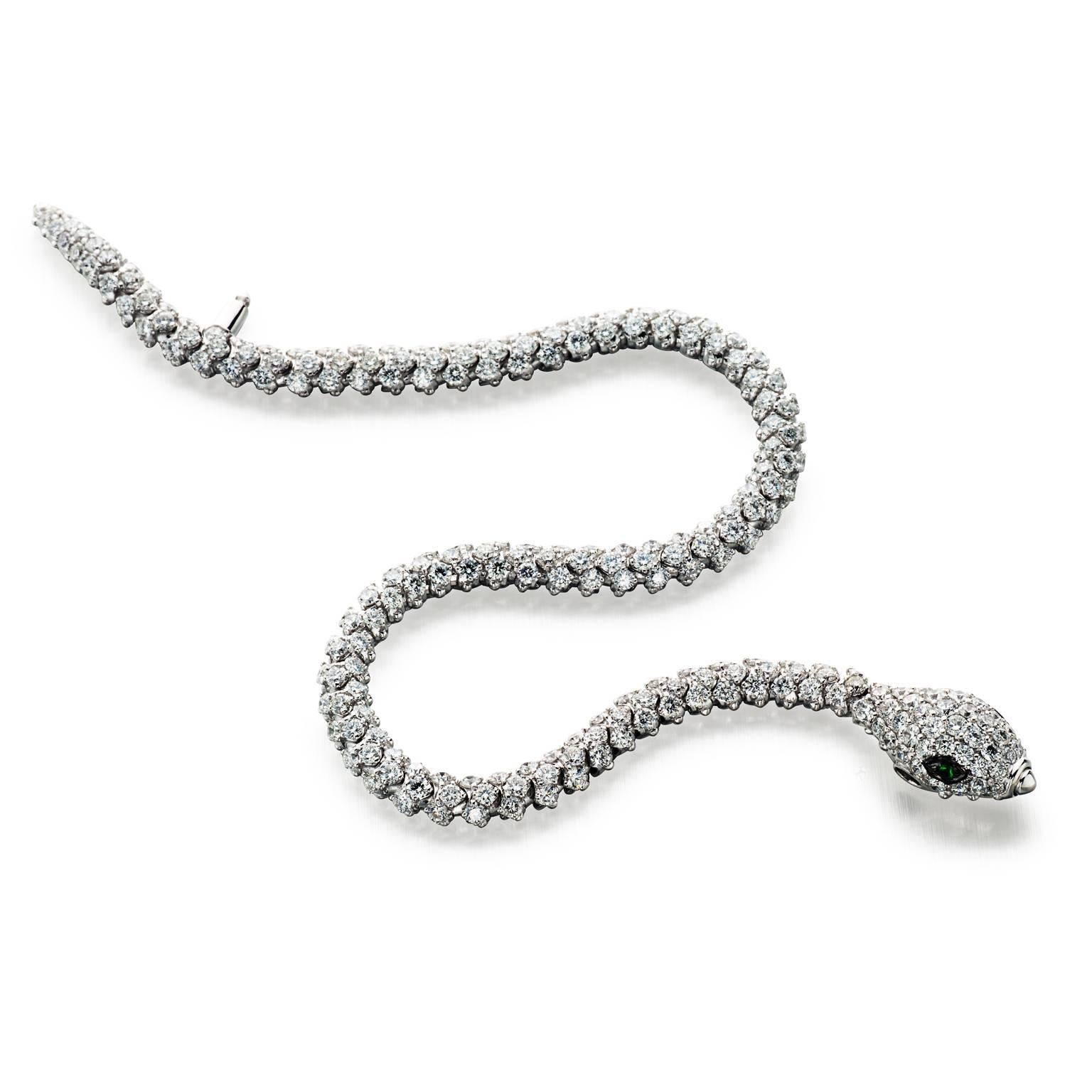 Stunning and exceptionally constructed. This fully articulated 18k white gold snake bracelet features 6.87 cttw diamond scales and polished scutes on underside. The head is detailed with 0.04 cttw green garnet eyes and a push button nose clasp