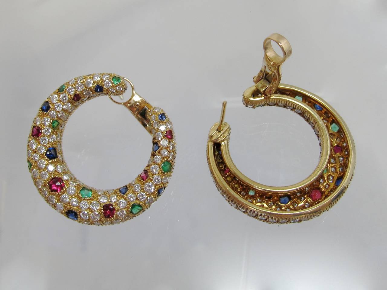 Vibrant colors!
Panthére diamond, sapphire, ruby & emerald creole-style hoop earrings,  
with  pavé -set round brilliant-cut diamonds & 42 buff-top sapphires, rubies & emeralds, with clips & posts backs.
18k gold

Signed:  Cartier 750