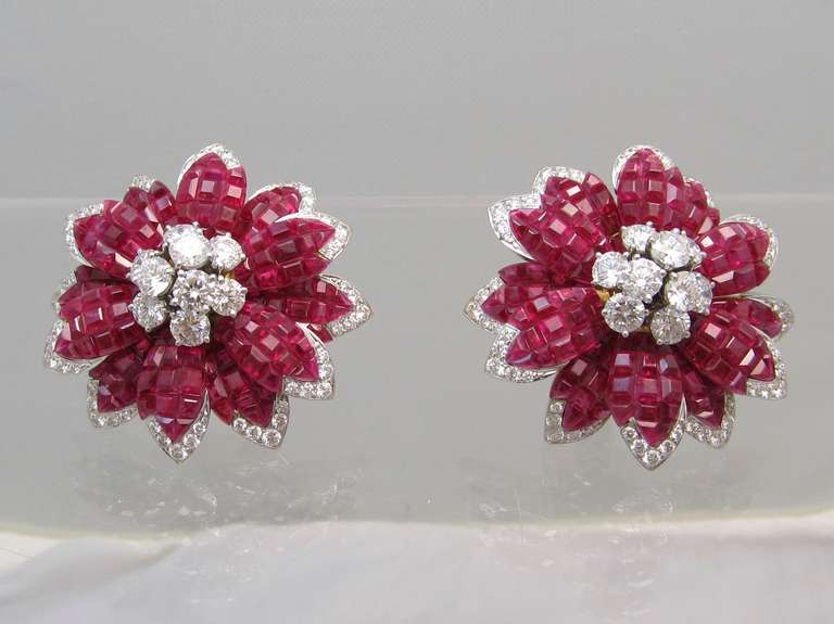 Alletto Brothers Ruby and Diamond Mystere style  flower design ear-clips.
At the center of each flower is an en-tremblant circular-cut diamond cluster pistil surrounded by en tremblant calibre-cut diamond trim.
Mounted platinum and 18k yellow