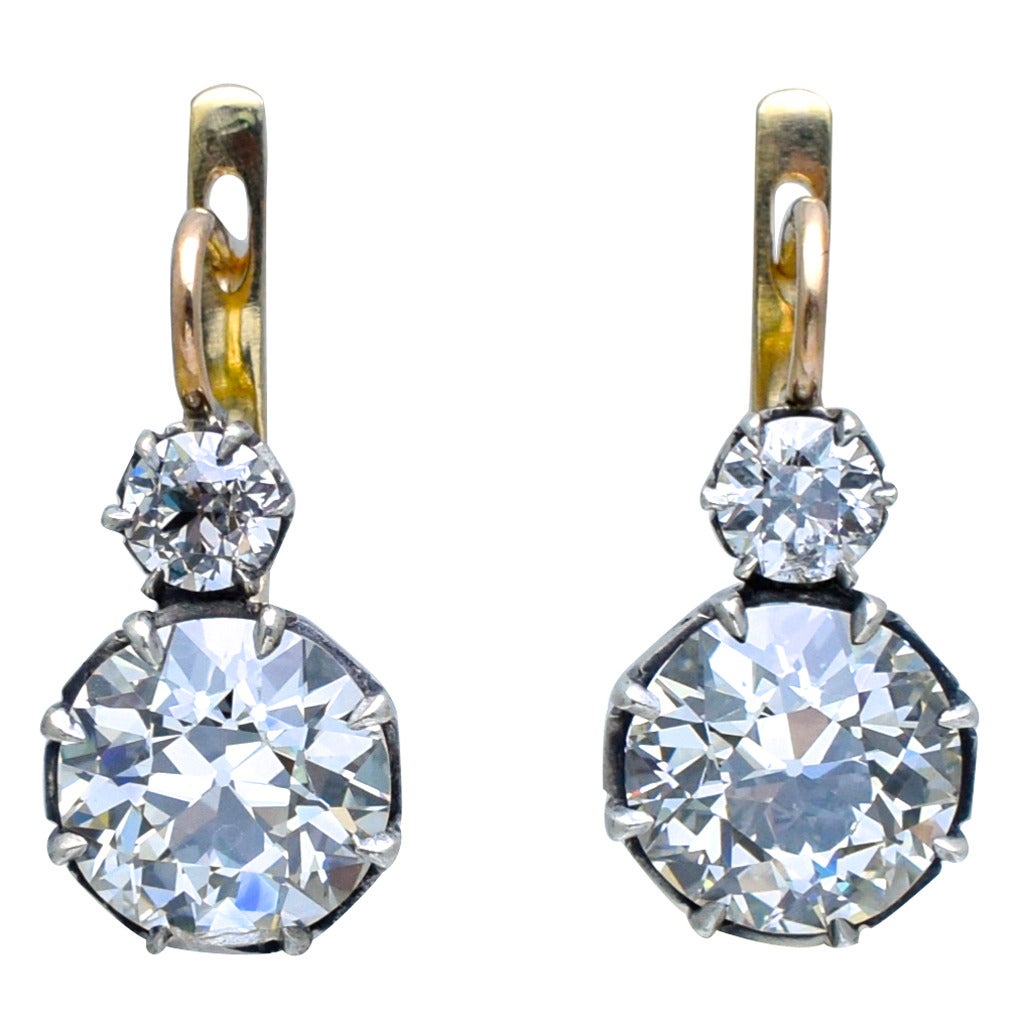 A pair of old European diamonds weighing 3.02 K color and VS2 clarity  and 3.04 K color VVS2 clarity with GIA reports are suspended from  2 old European diamonds weighing  total approximately 1.10 carat. Mounted in antique style silver top and ellow