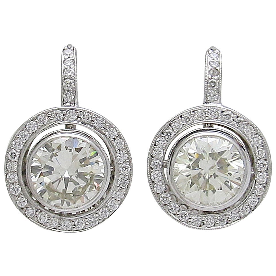Impressive diamond earrings

Two brilliant shape diamonds set in a filigree bezel style and surrounded by a second tier gold  encrusted with 64 diamonds.

Two center diamonds are with total weight of 6.16 carats and are near colorless range.

Total