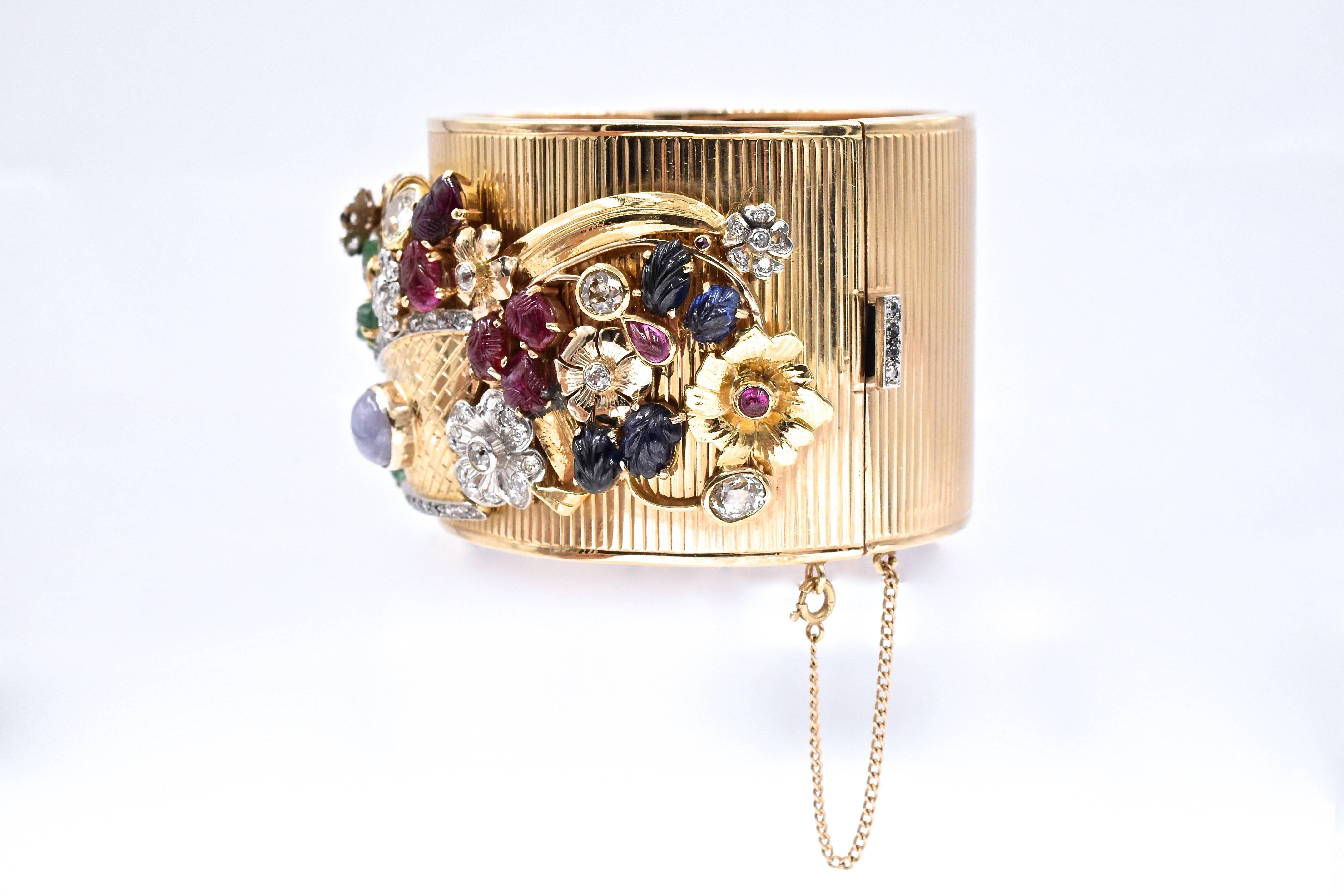 Retro! circa 1940's  rose gold fluted design bangle with diamonds, sapphires, rubies and emeralds flower basket motif overlay. with internal circumference of approx. 6.5 inches. 
Measurements: 
Width: 40mm
Wrist size: 6 inches