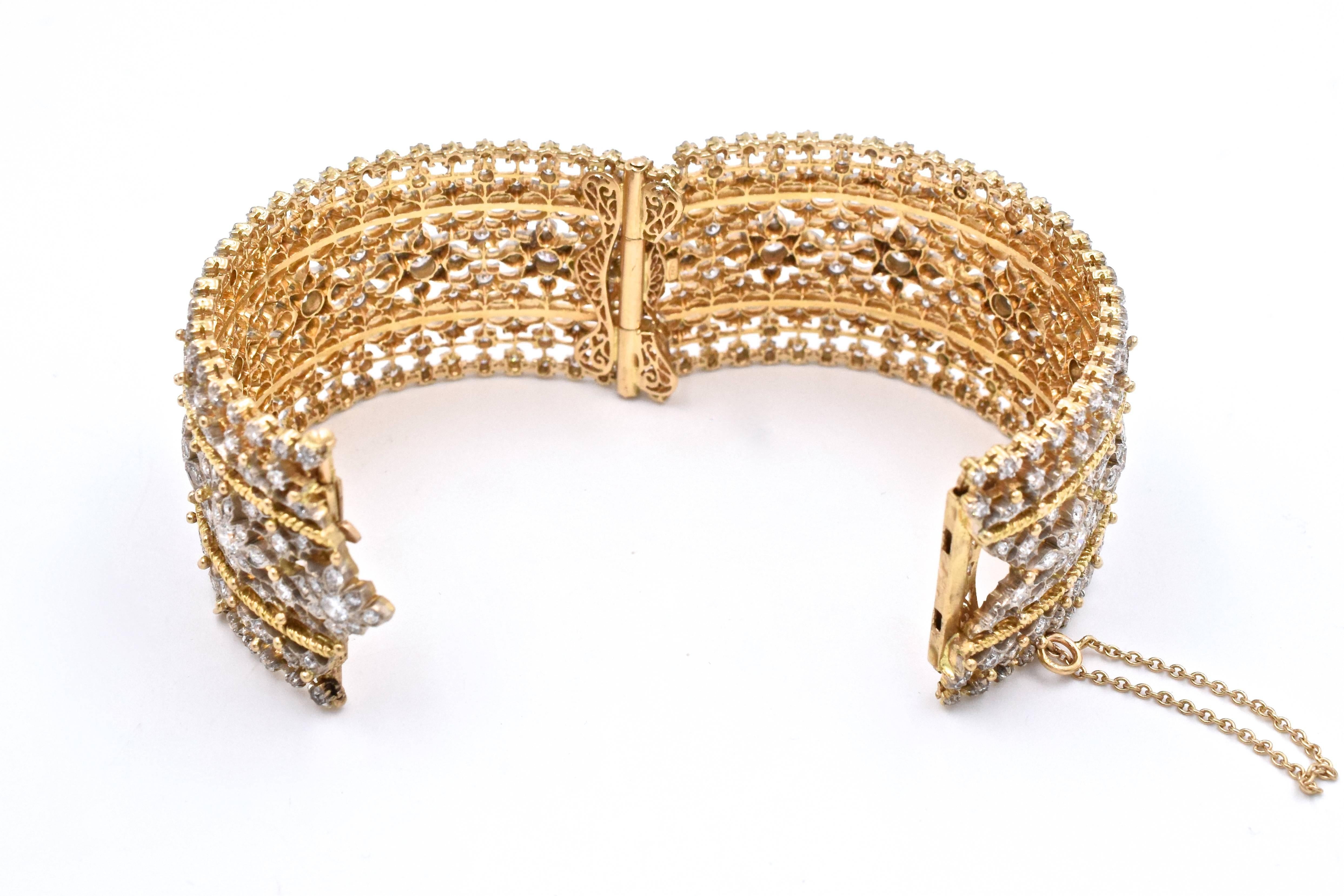 Two-Color Gold and Diamond Cuff Bangle Bracelet,
The delicate openwork cuff centering a line of florets, set throughout with round diamonds approximately 12 carats total weight.
18k gold
 Inner circle 7 inches. Width 1 3/16 inches.