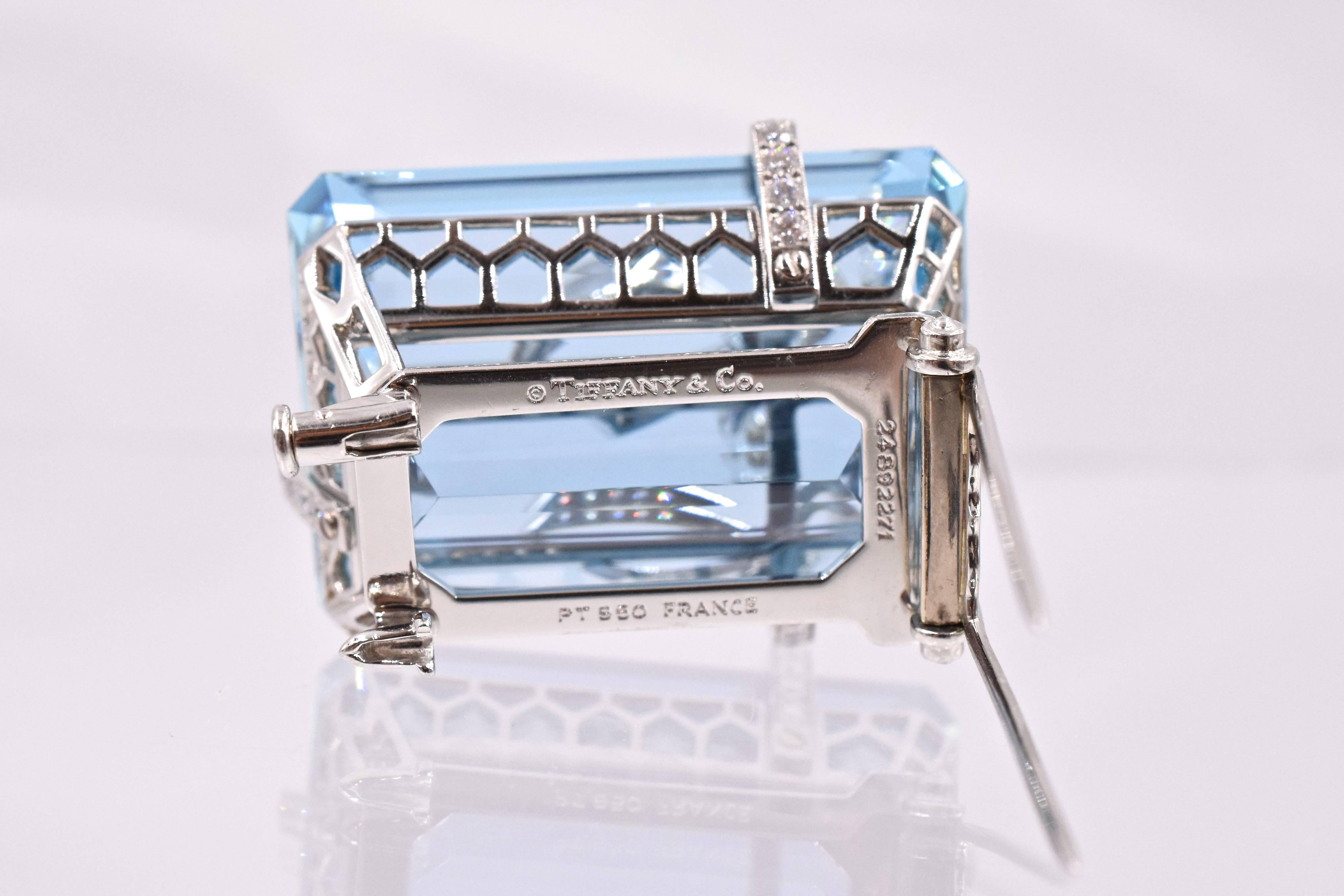 An Aquamarine and Diamond Brooch, by Tiffany and  Co. Set with a rectangular-cut aquamarine, weighing approximately 91.03 carats, wrapped with a circular-cut diamond ribbon and bow, 
Measurement is1 ⅜ ins    mounted in platinum.
 Signed Tiffany and