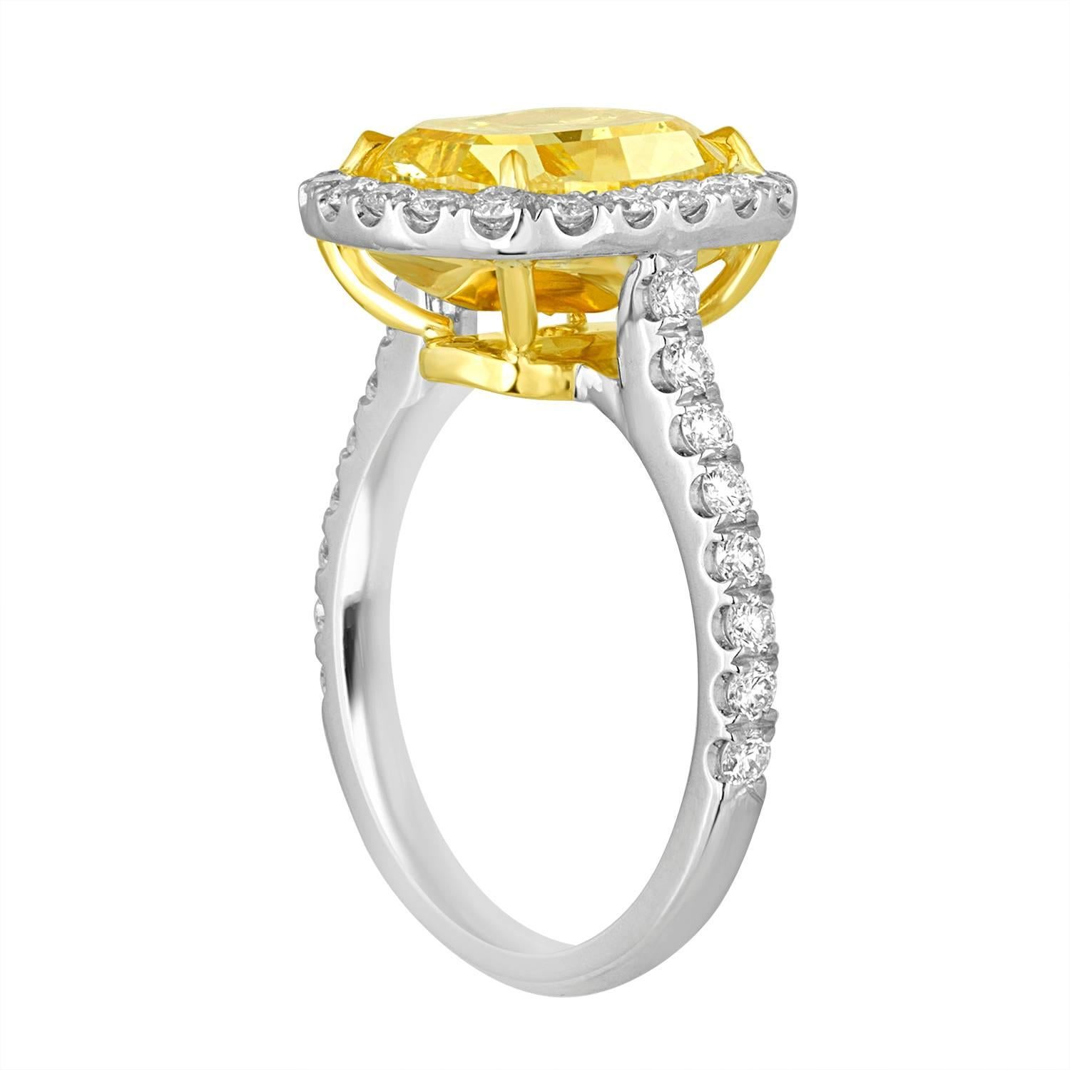 4.76 Carat Cushion Shaped Diamond is GIA certified as Fancy Vivid Yellow in Color and SI2 in Clarity. The Diamond is full of life and beauty. The Cushion is set in Two Tone Mounting with 70 Brilliant 1.54 Carat Total Weight in Halo settings. White