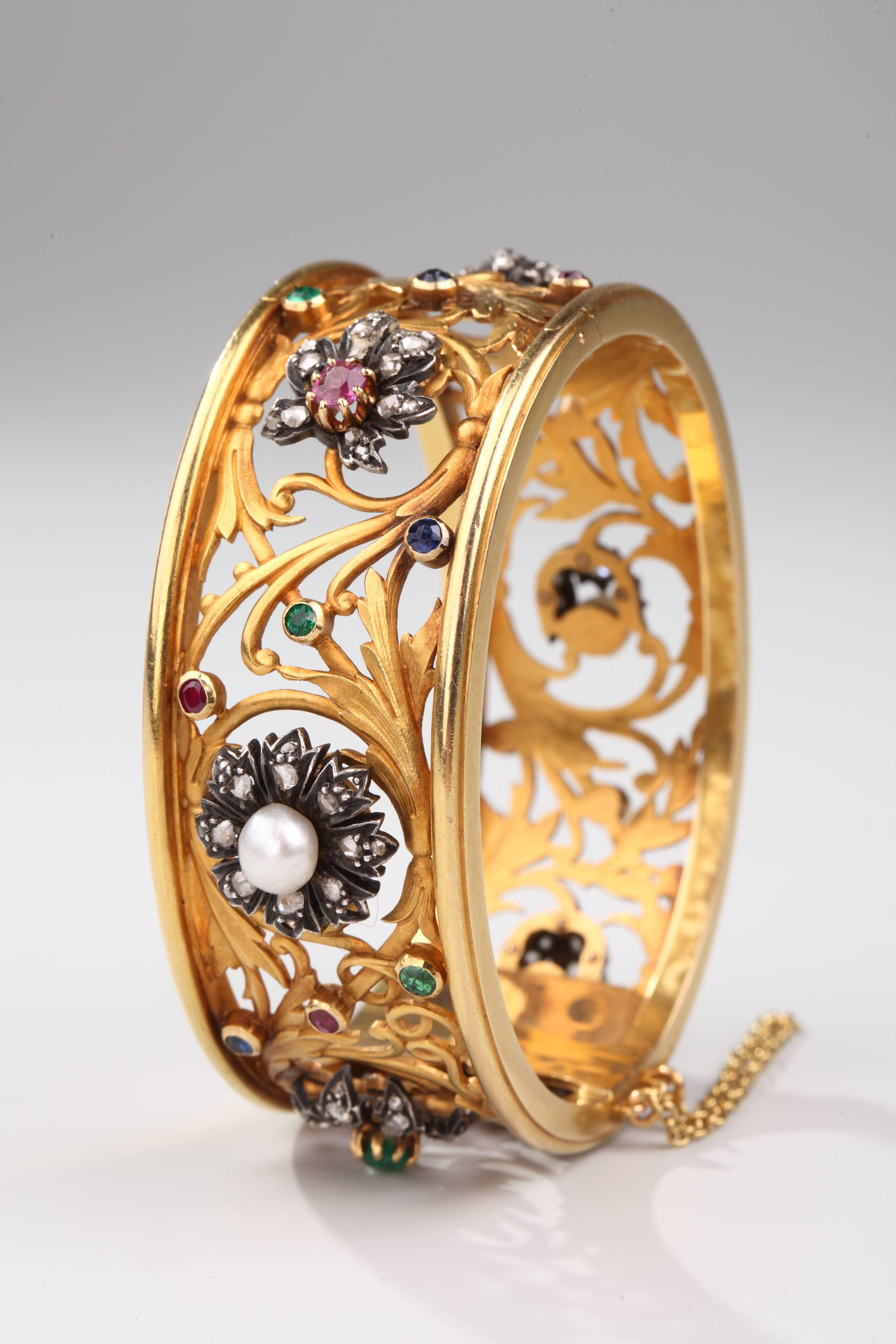 Magnificent cuff bracelet in 18k yellow gold adorned with a delicate frieze of foliage in chiseled gold set with rose cut diamonds, emeralds, rubies, sapphires and pearls.
French assay marks for gold.
