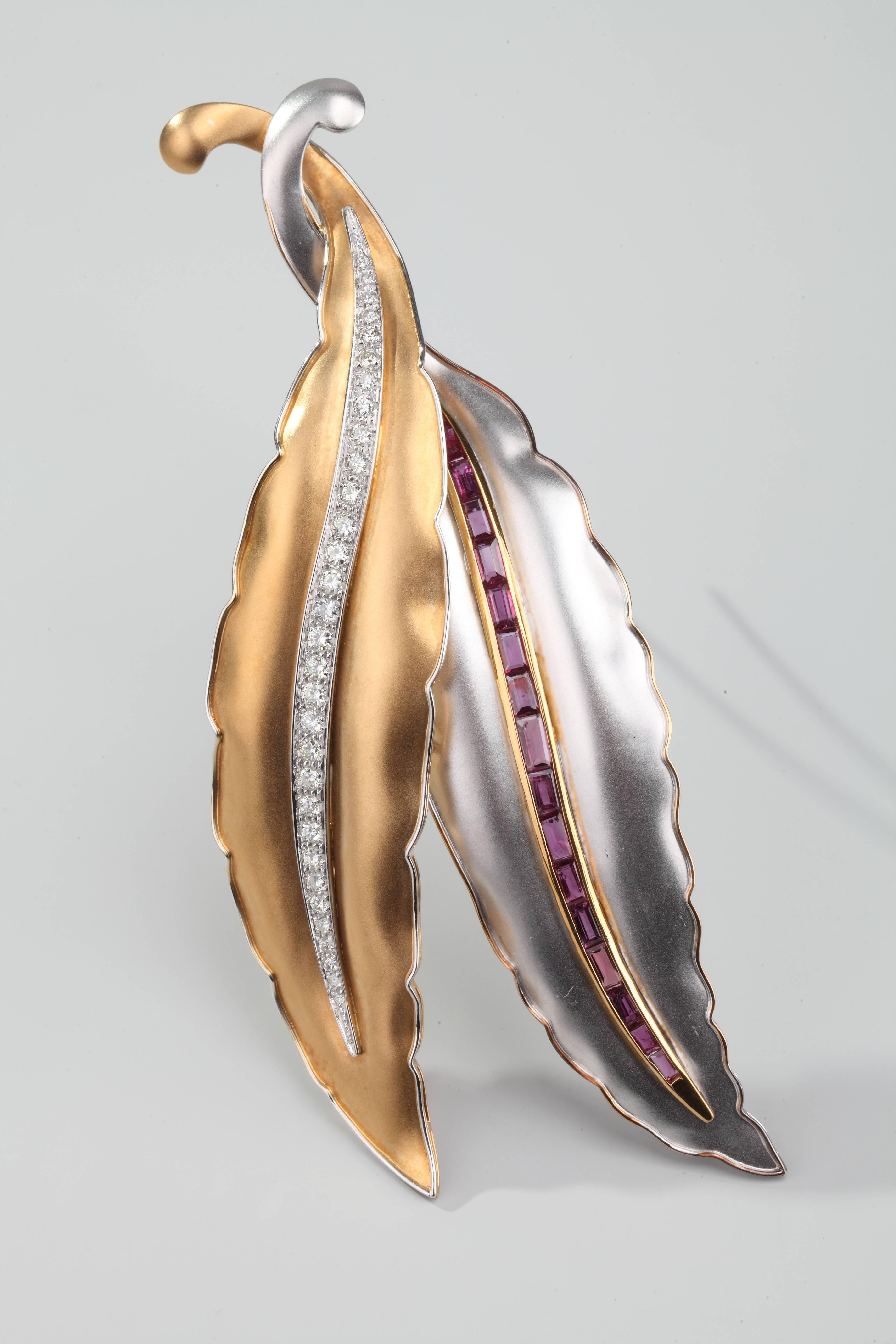 Brooch in the shape of two leaves, one in yellow sanded gold, one in white sanded gold, the ridge set, one with brillant cut diamonds, the other with baguette cut rubies.