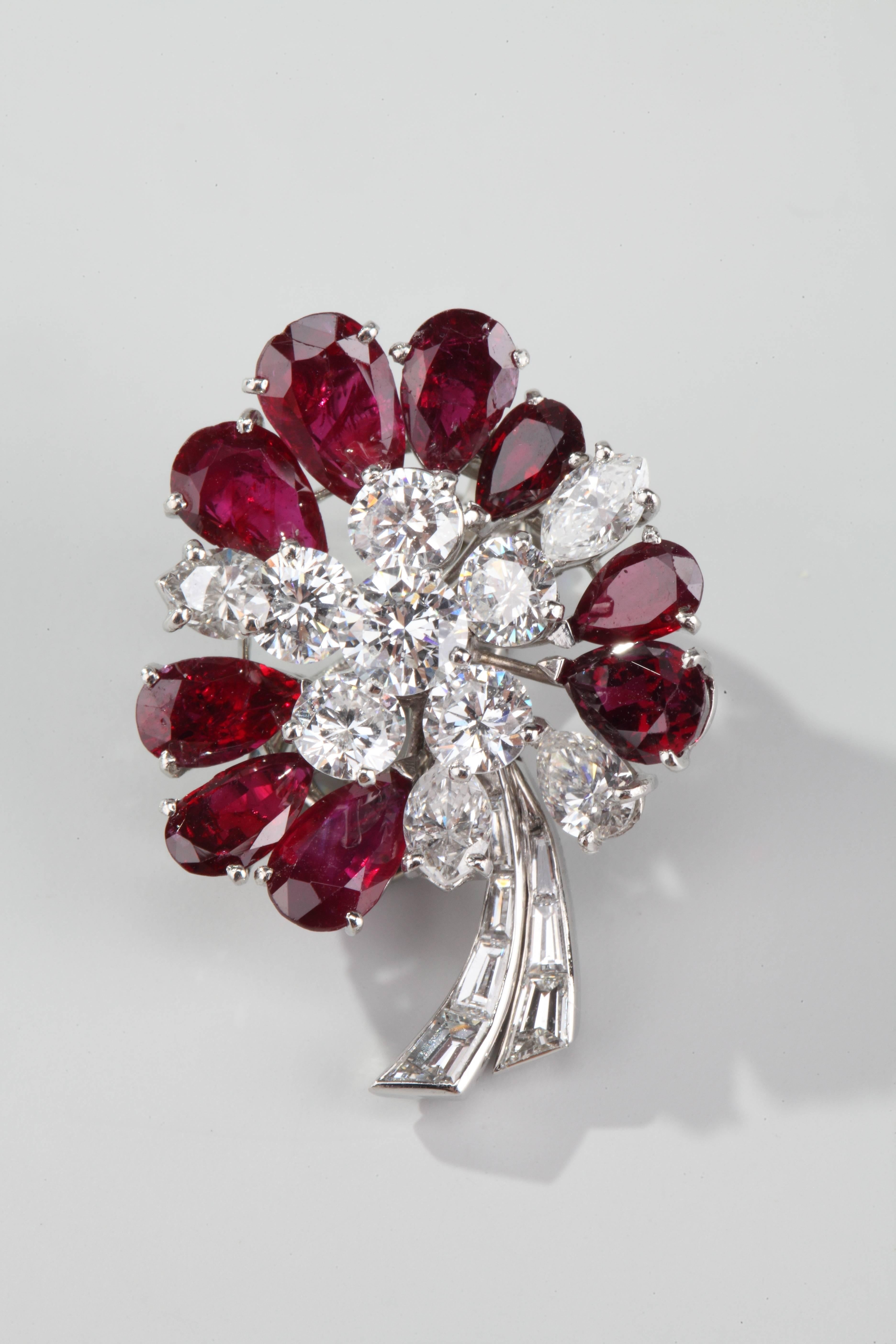 Stylizing a flower in platinum and gold, set with pear-shaped rubies and round and marquise-cut diamonds, the stem with tappers cut diamonds.